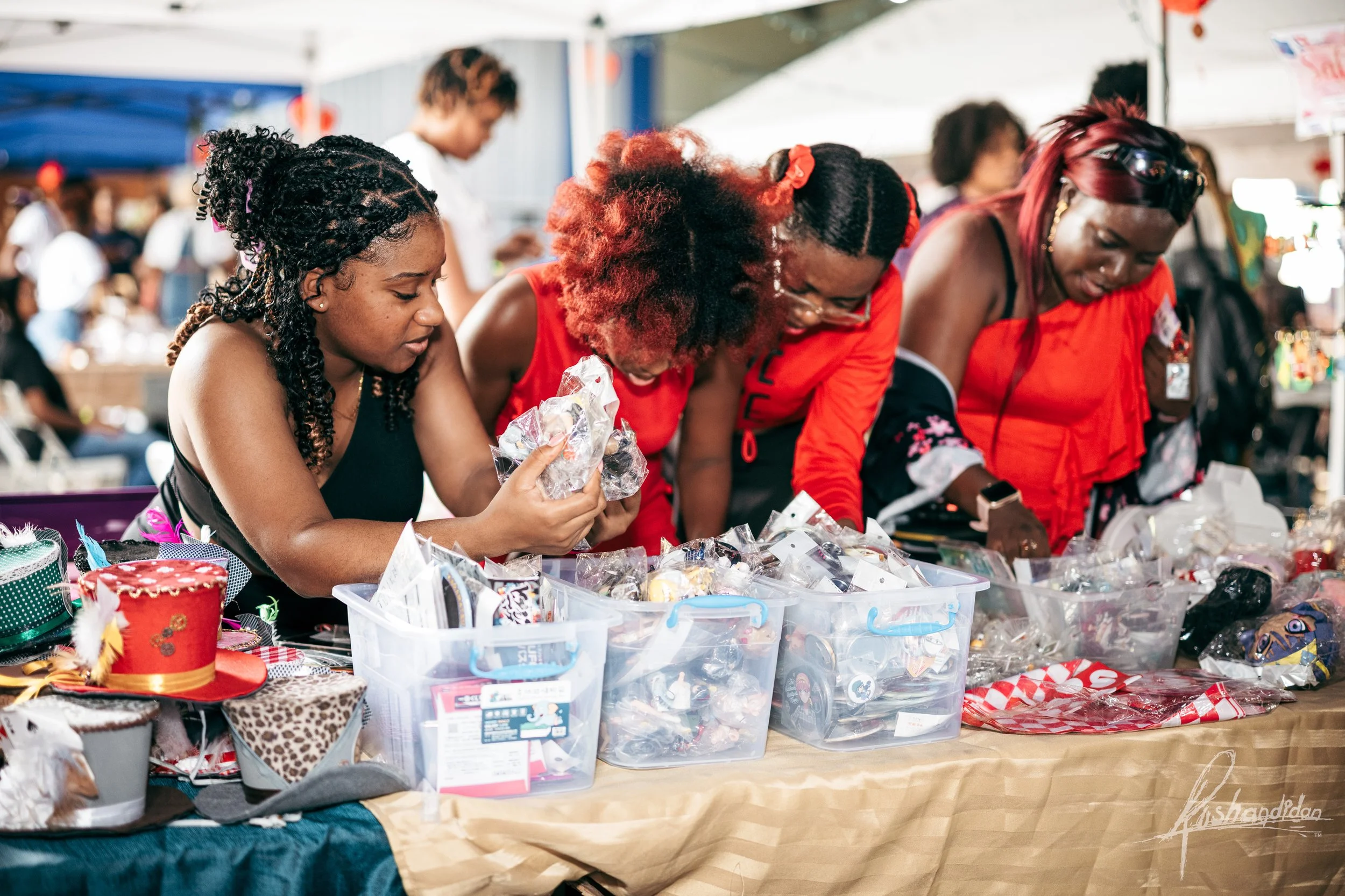 Four women shopping for Christmas accessories at an outdoor market stall, looking through various holiday items.