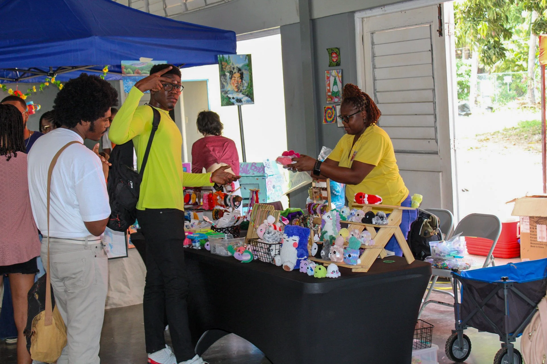 People shopping at a craft fair booth displaying colorful handmade plush toys and accessories.