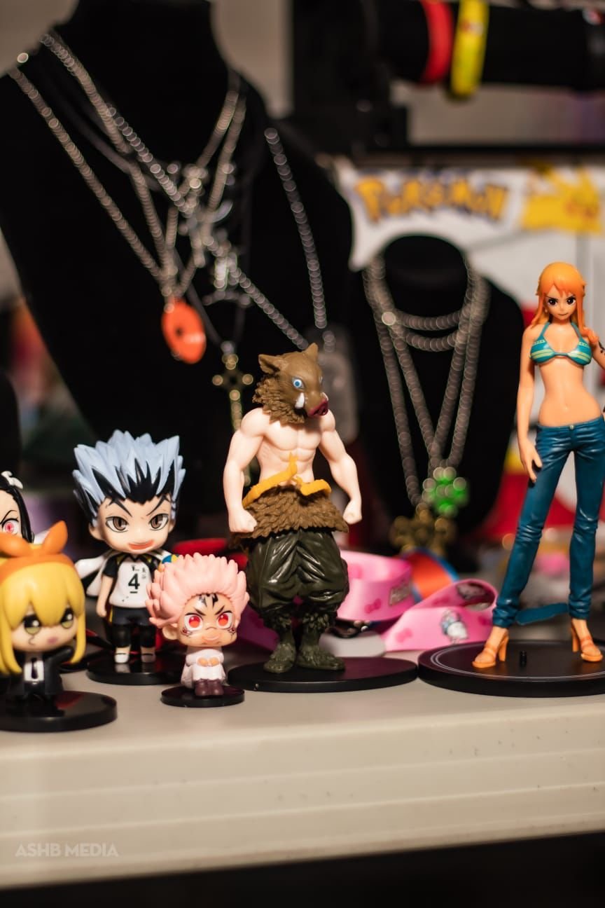Collection of anime and cartoon character figures on a shelf with jewelry and accessories in the background.