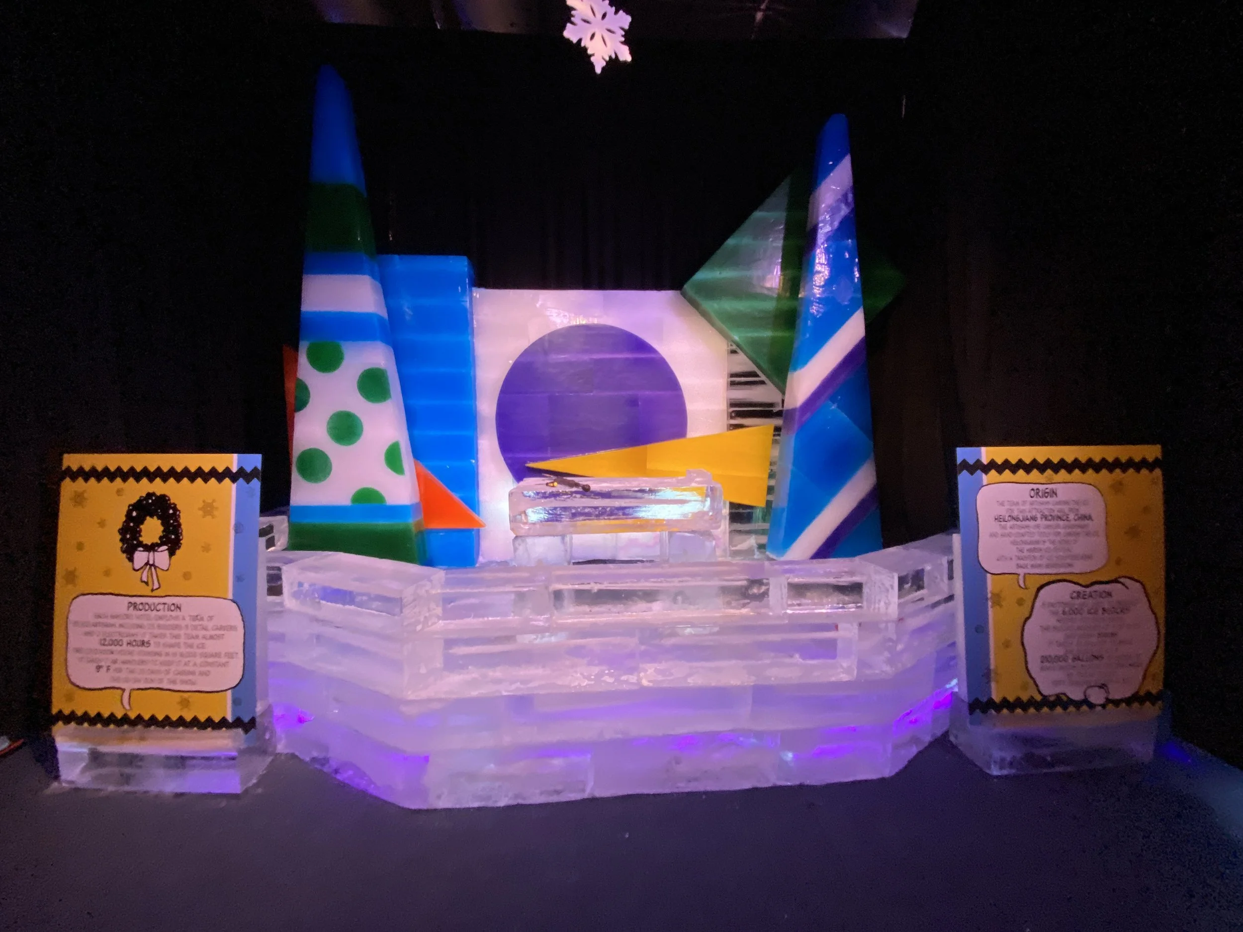 Colorful light display on ice sculpture with polka dot pattern and informational plaques on each side.