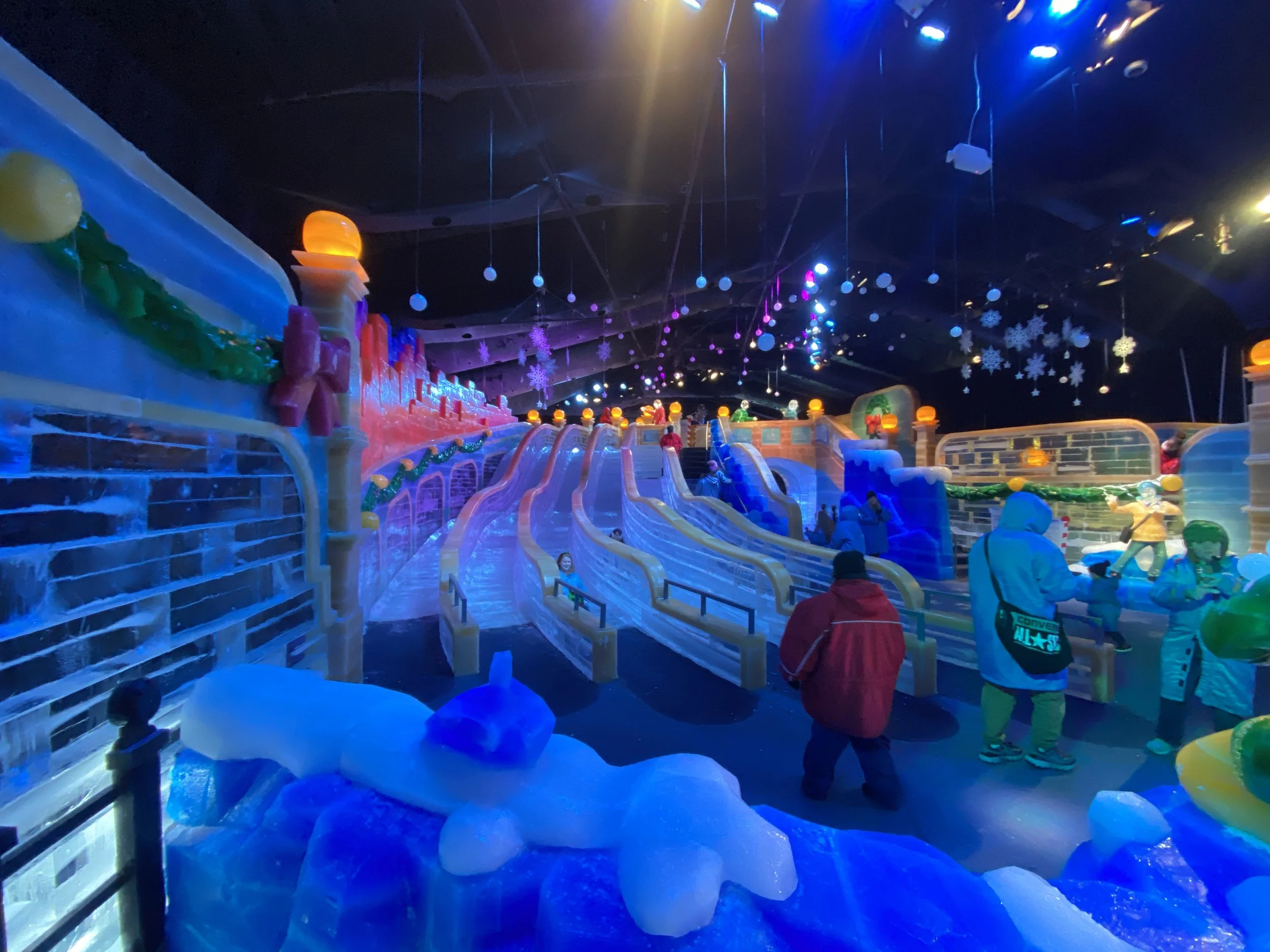 Indoor ice skating rink decorated for winter with snowflakes, colorful lights, and festive decorations, with children skating.