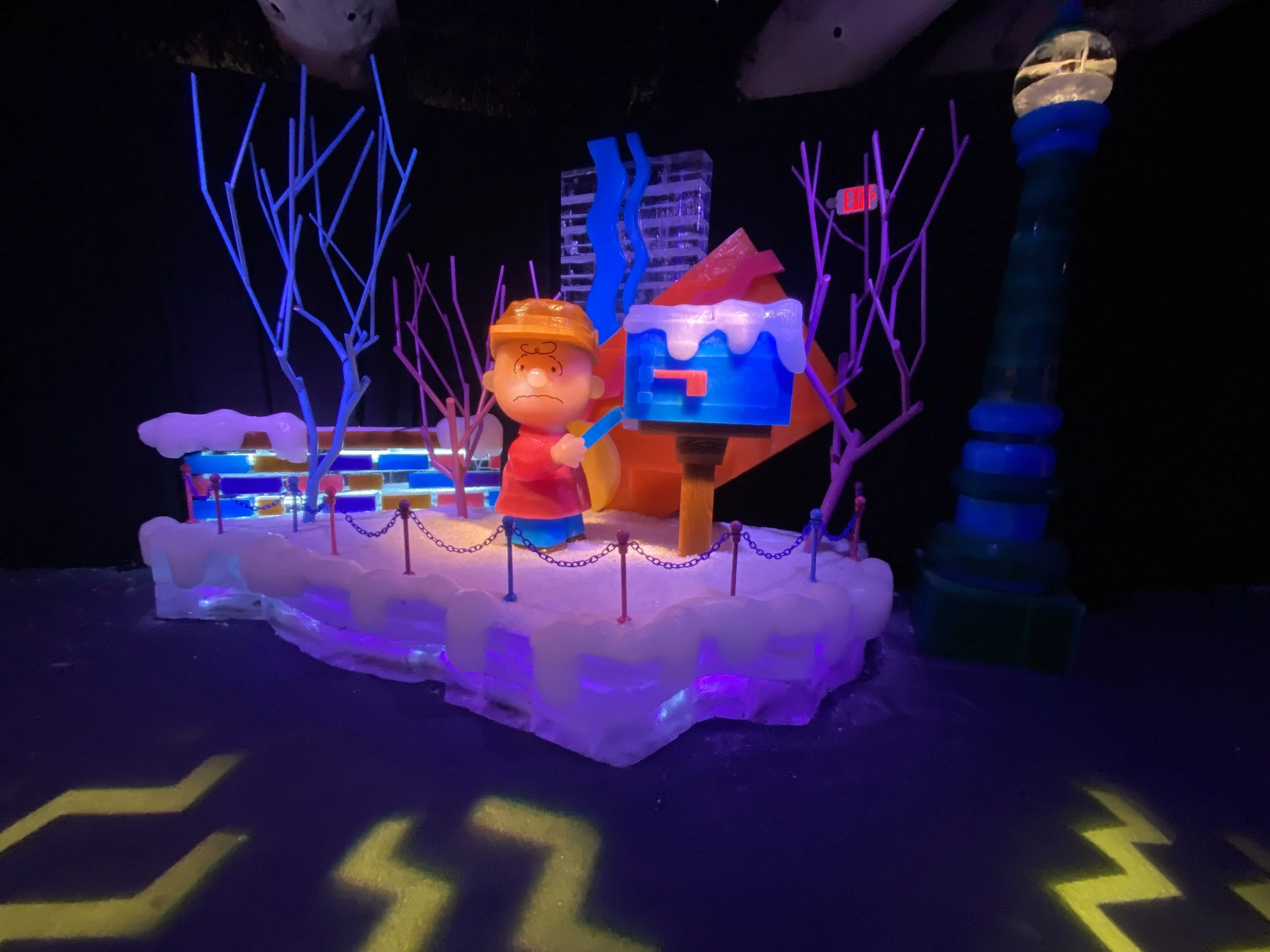 Colorful animated display featuring a cartoon boy holding a mailbox, surrounded by trees and structures with glowing lights, set in a dark environment.