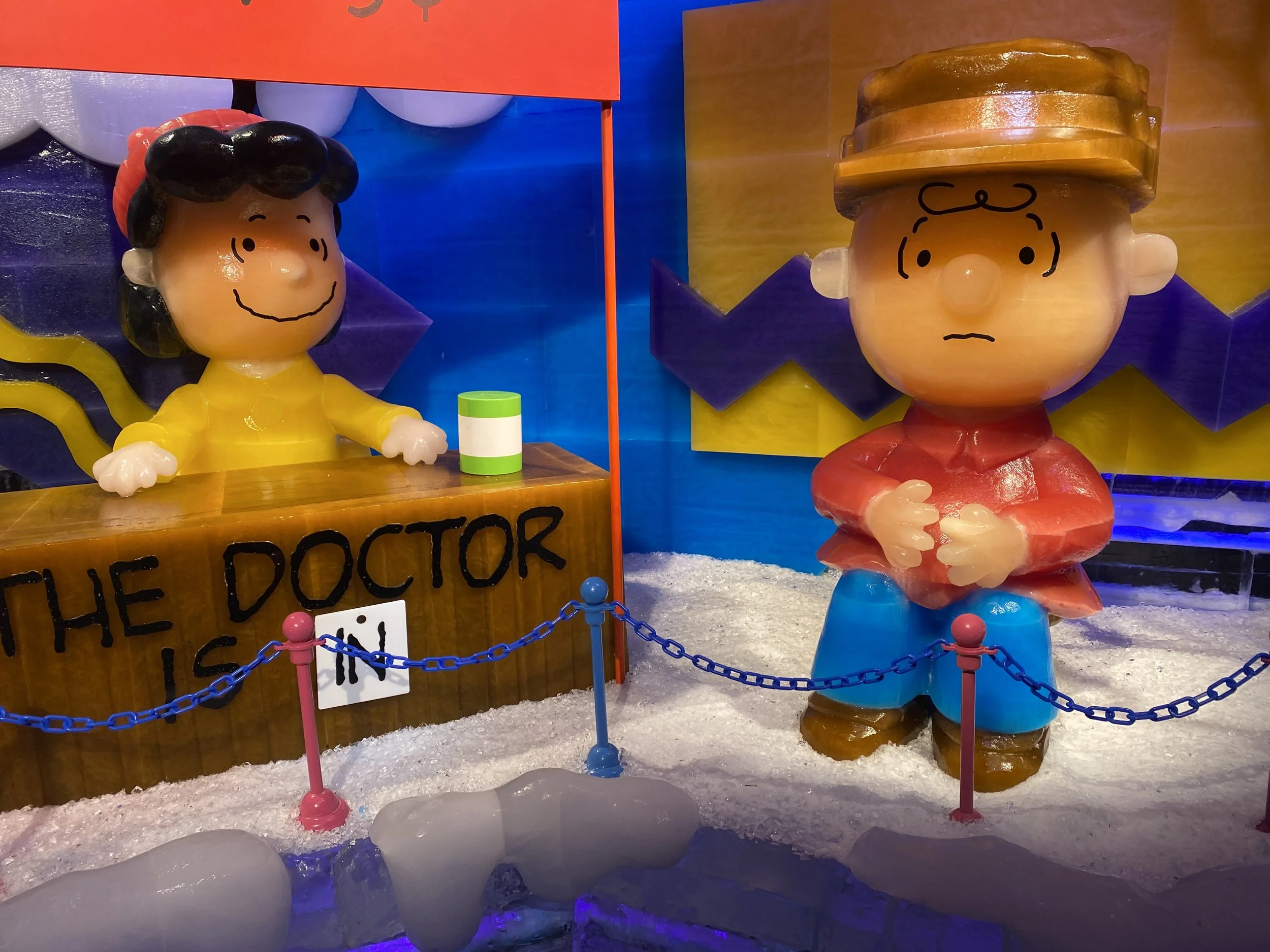 Ice sculpture of Charlie Brown and Lucy Van Pelt from Peanuts, with colorful background, divided into two parts.
