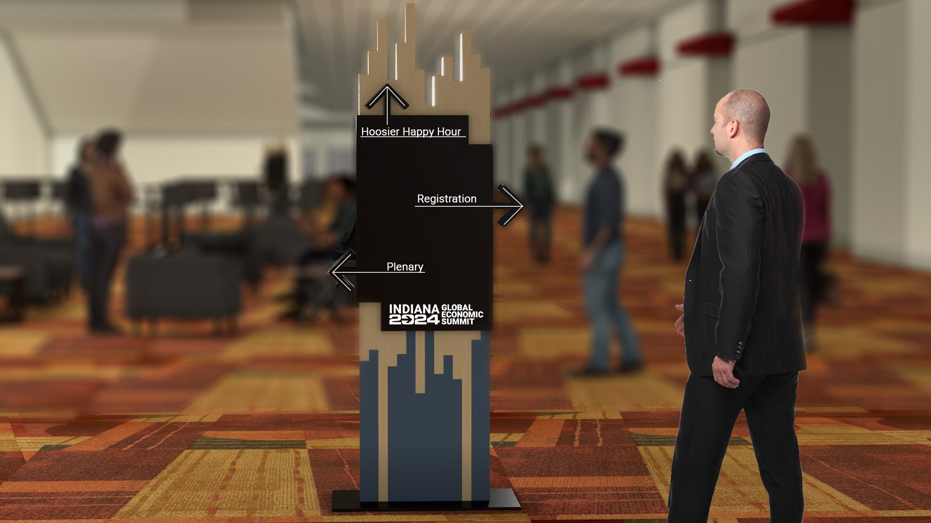 A man in a black suit standing in a conference hall with a colorful carpet, looking at an event sign that reads 'Indiana 2024 Global Economic Summit' and has arrows pointing to 'Hoosier Happy Hour,' 'Registration,' and 'Plenary.' Blurred background s