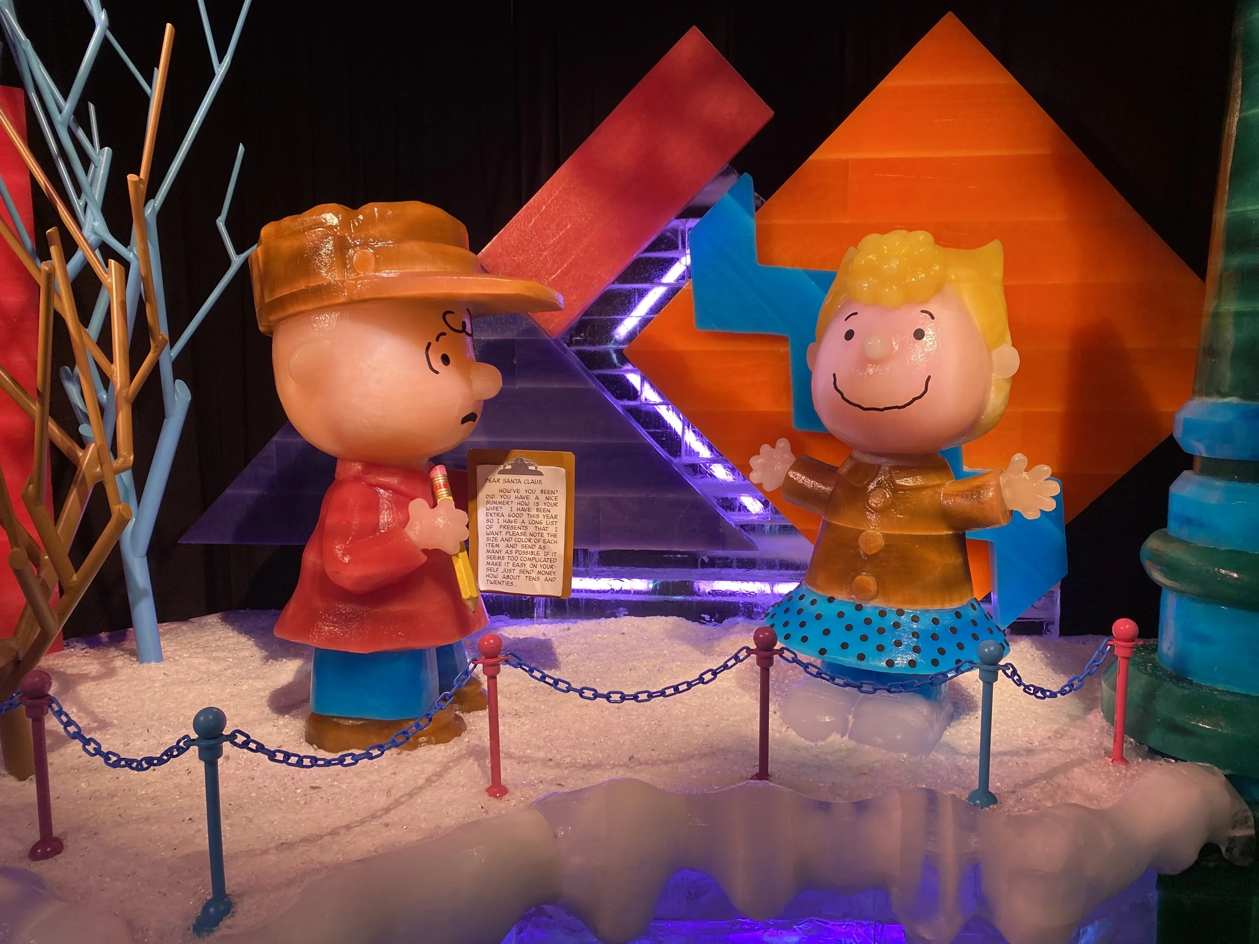 Decorative display of cartoon-like characters with exaggerated facial features and bright colors, set against a colorful background with geometric shapes and purple lighting.