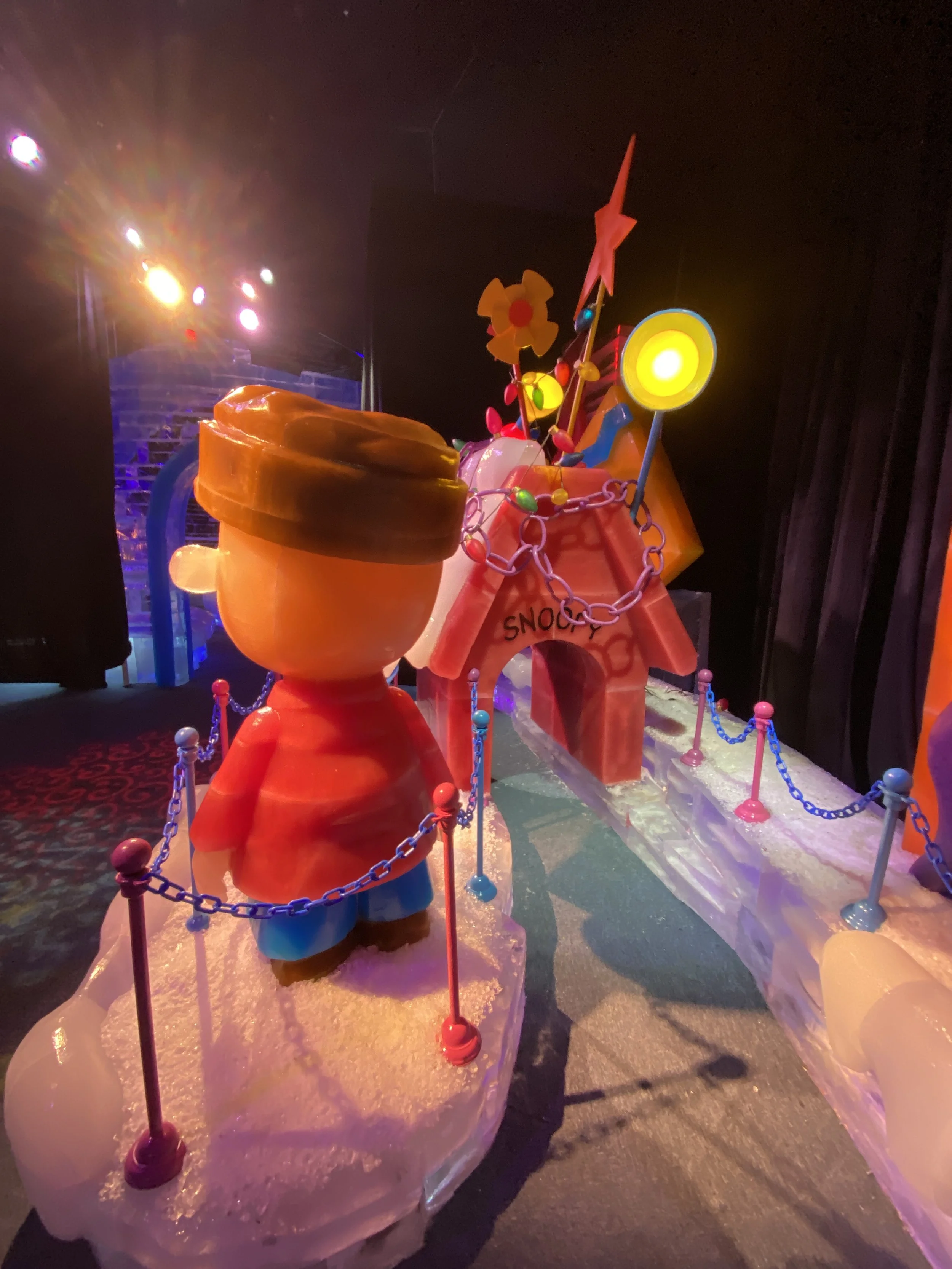 Colorful display with large cup, chain, flowers, star, and target shapes on an ice platform, illuminated by bright stage lights.