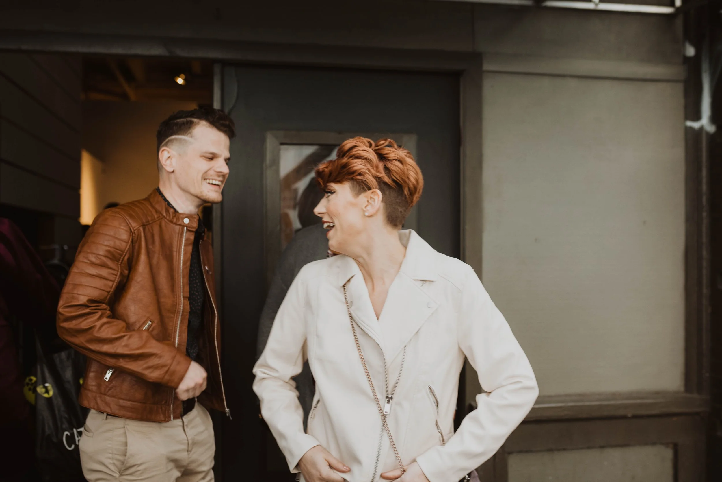 Two people, a man and a woman, are smiling and talking to each other outside a building. Pioneer Square, Seattle, WA wedding photography.