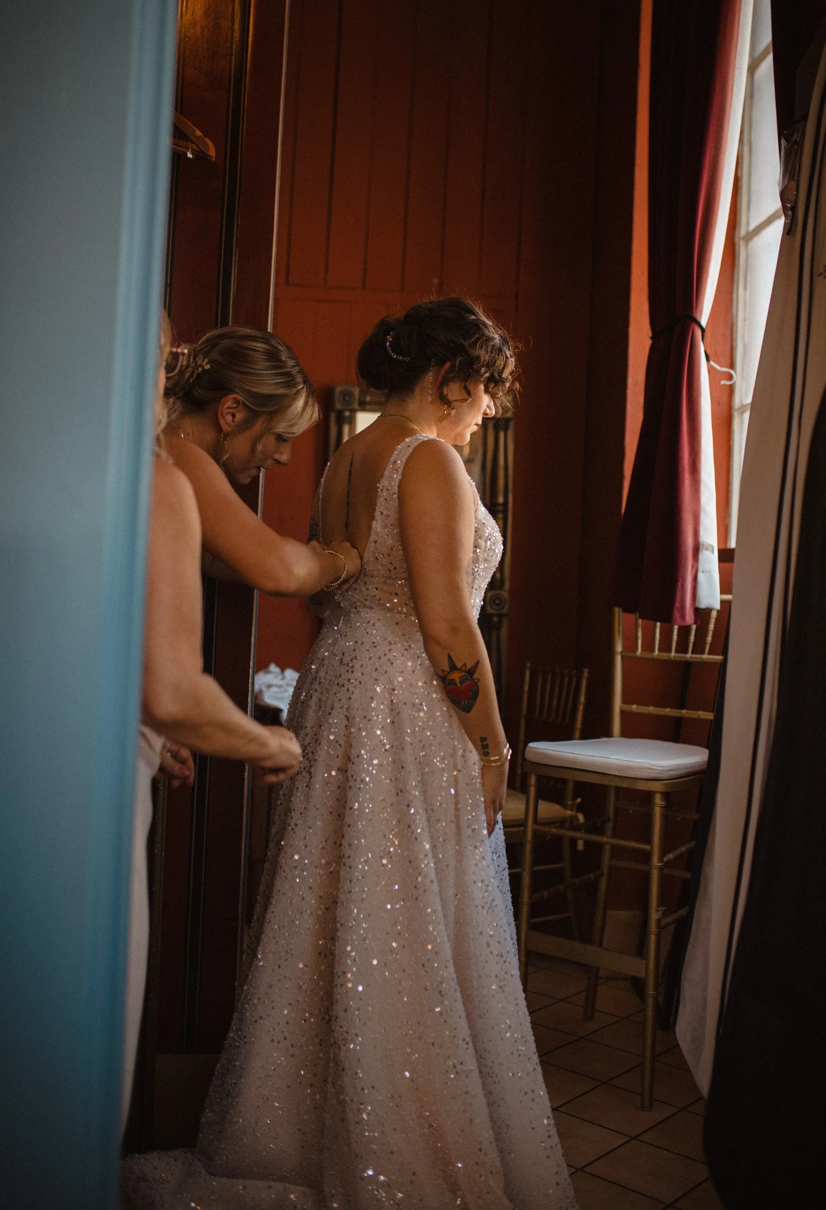 Maid of honor helps zip bride into her dress in the bridal sweet and The Ruins in Queen Anne, Seattle