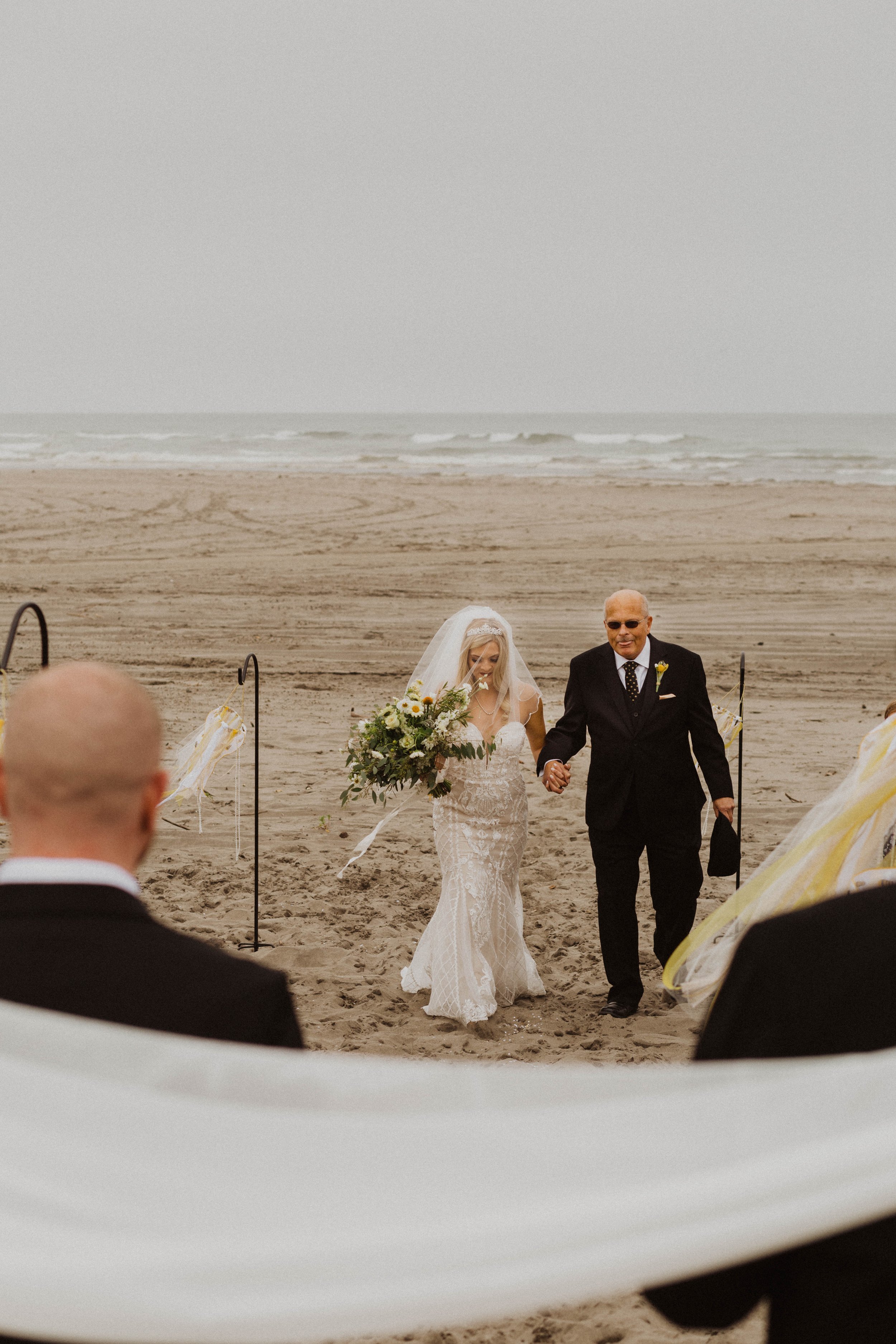 Bride walking down the beach aisle with her father during a beach wedding ceremony. Long Beach, WA wedding photography.