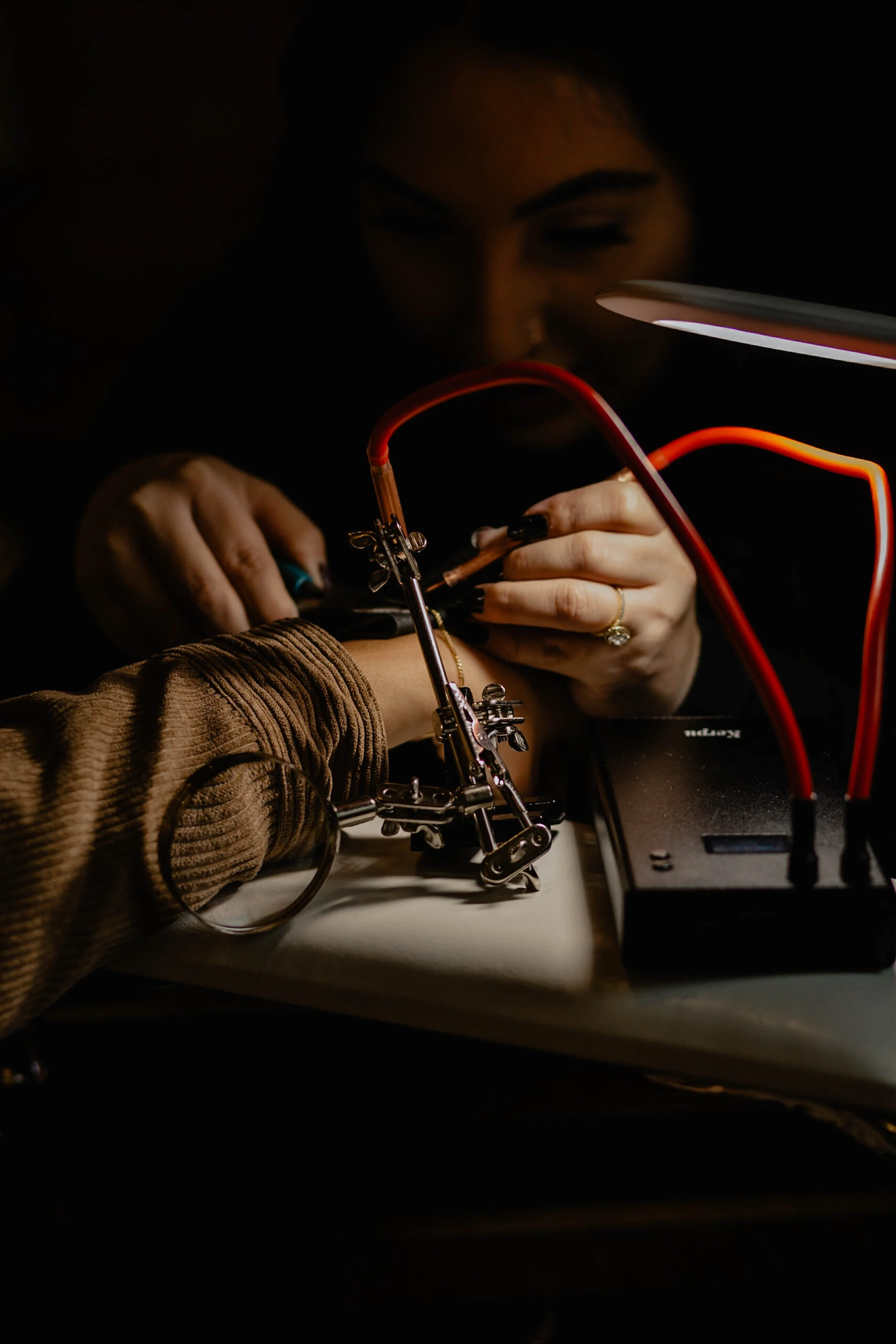 A person getting a tattoo on their wrist while a tattoo artist works with tattooing equipment under a bright light. Seattle professional head shot photography