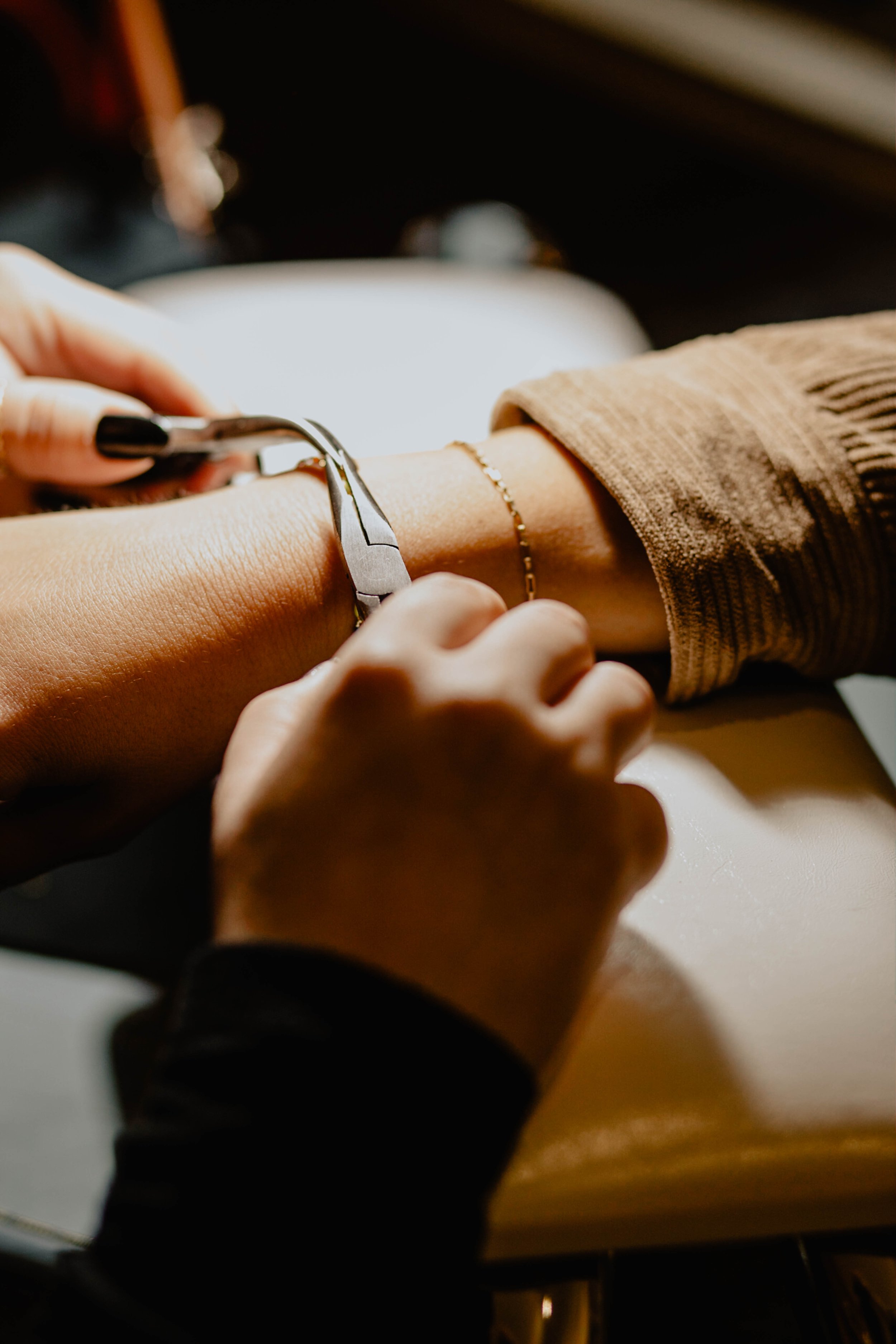 A person getting a gold bracelet on their wrist at a jewelry shop or workshop. Seattle professional head shot photography