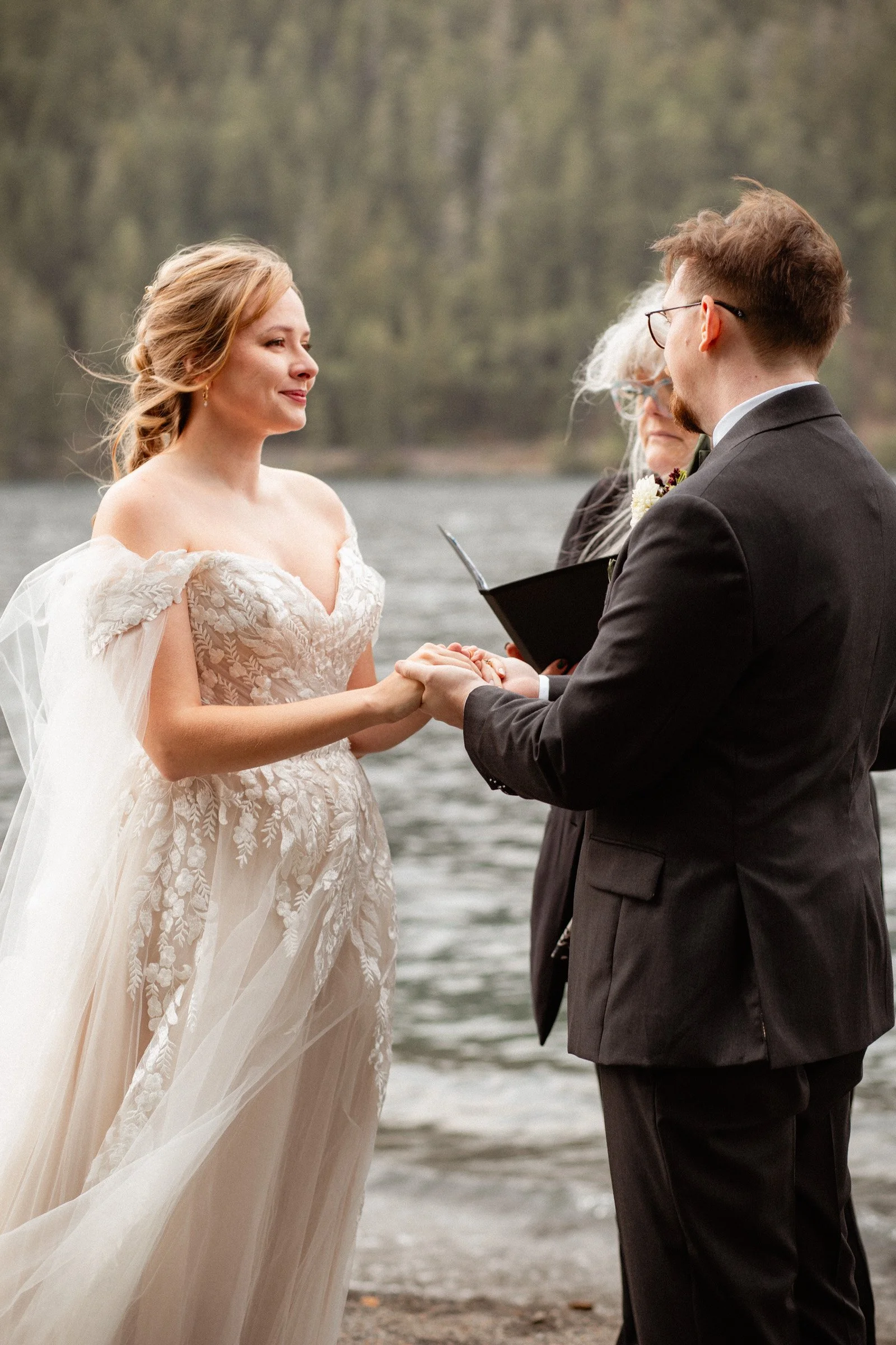 Groom holding the bride’s hands at the altar and smiling at her during their Lake Crescent Lodge wedding ceremony in Port Angeles, WA.