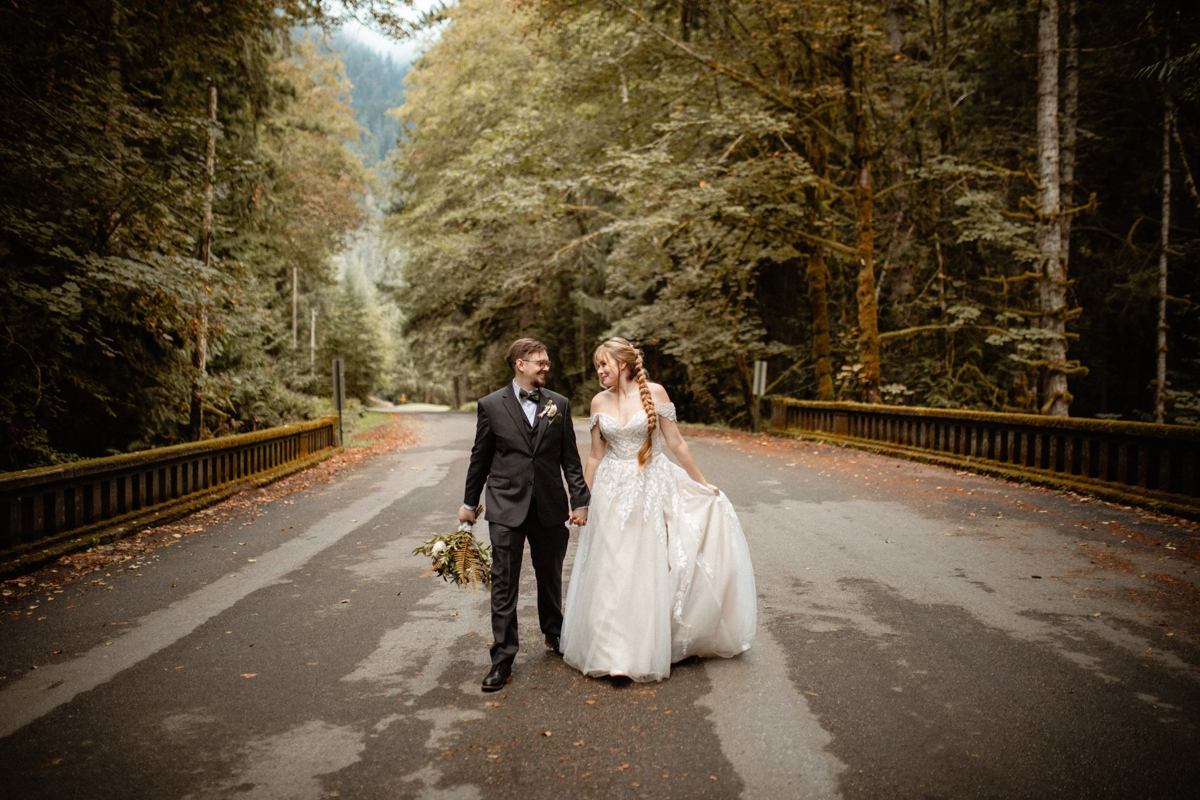 Bride and groom walking hand-in-hand through the forest during their Lake Crescent wedding at Lake Crescent Lodge.