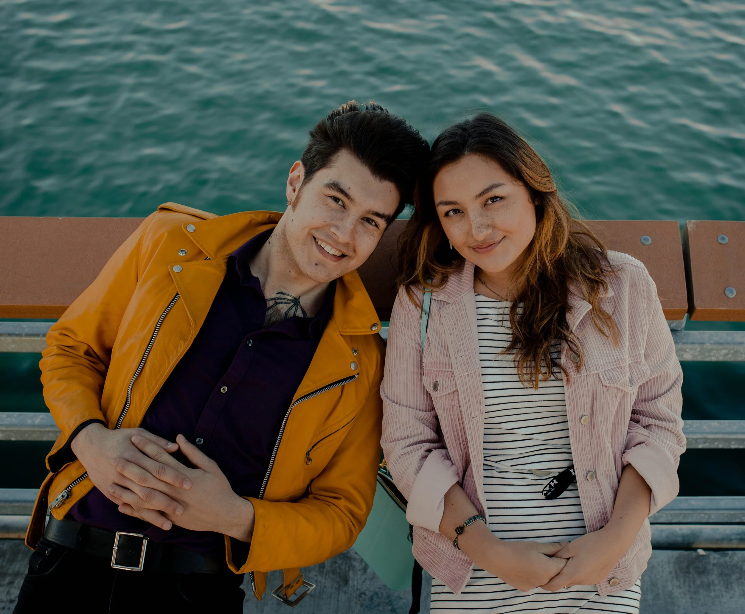 A young man and woman standing close together on a pier, smiling, with water in the background. Seattle professional head shot photography
