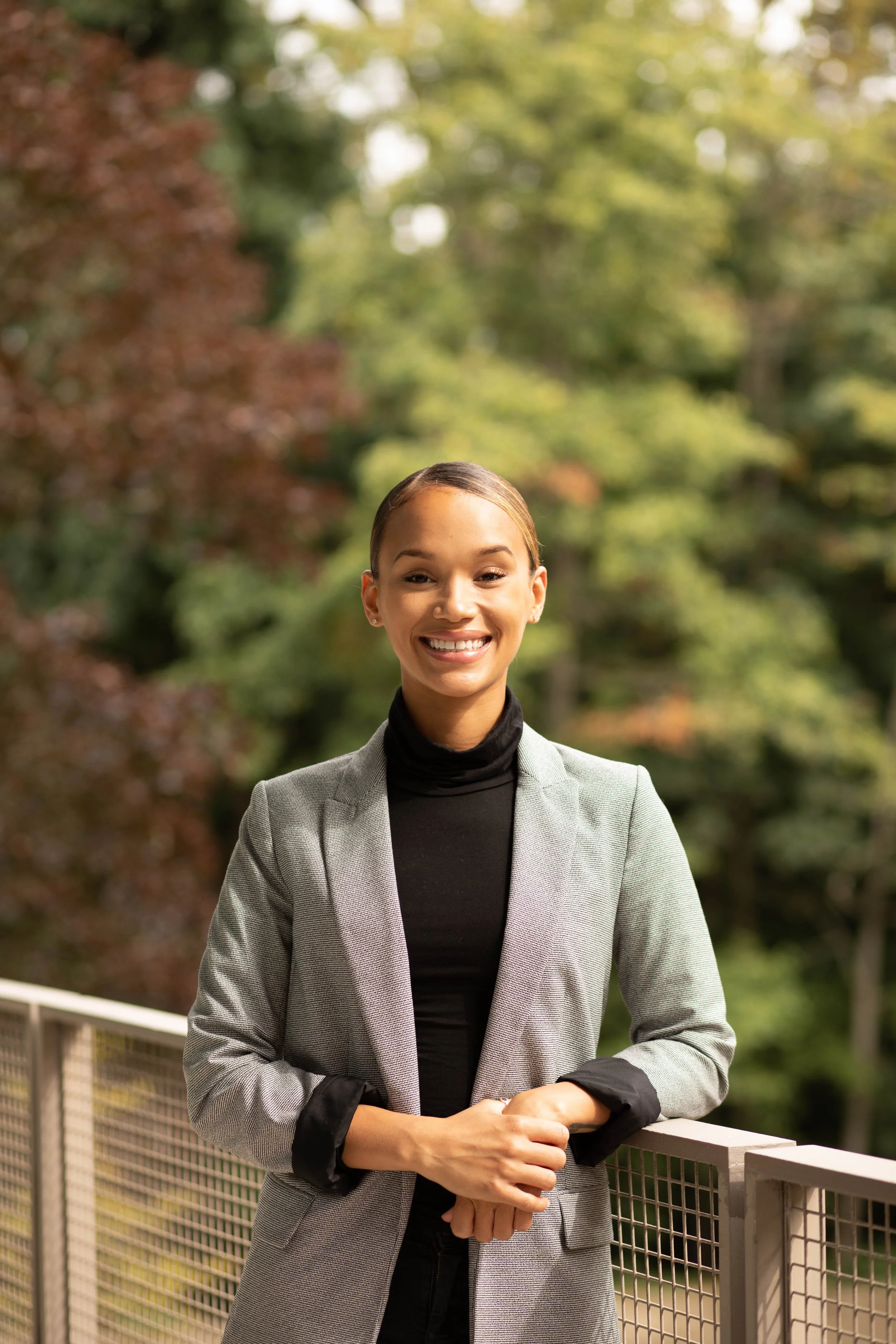 A woman smiling outdoors on a balcony with trees in the background. Seattle professional head shot photography