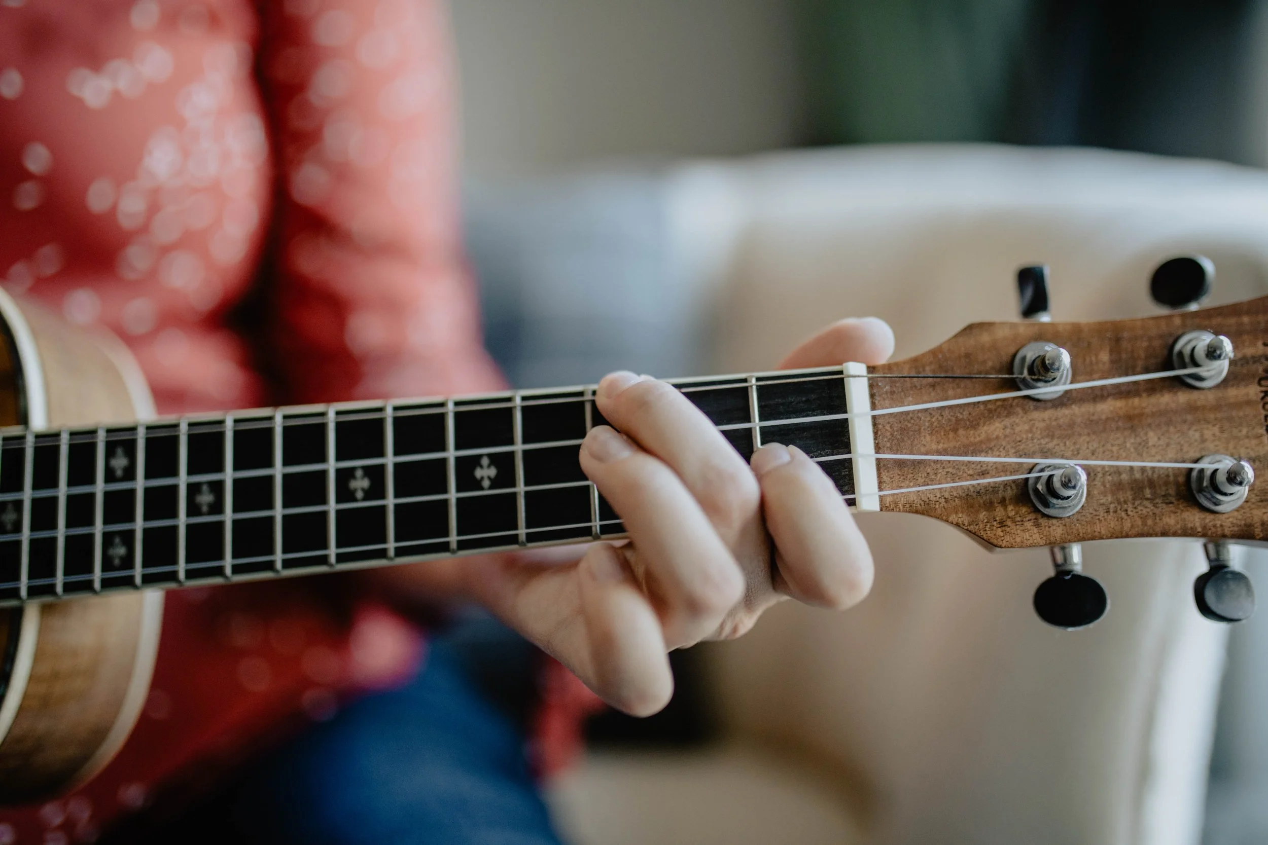 Person playing a guitar, focusing on their hand pressing the strings on the fretboard. Seattle professional head shot photography