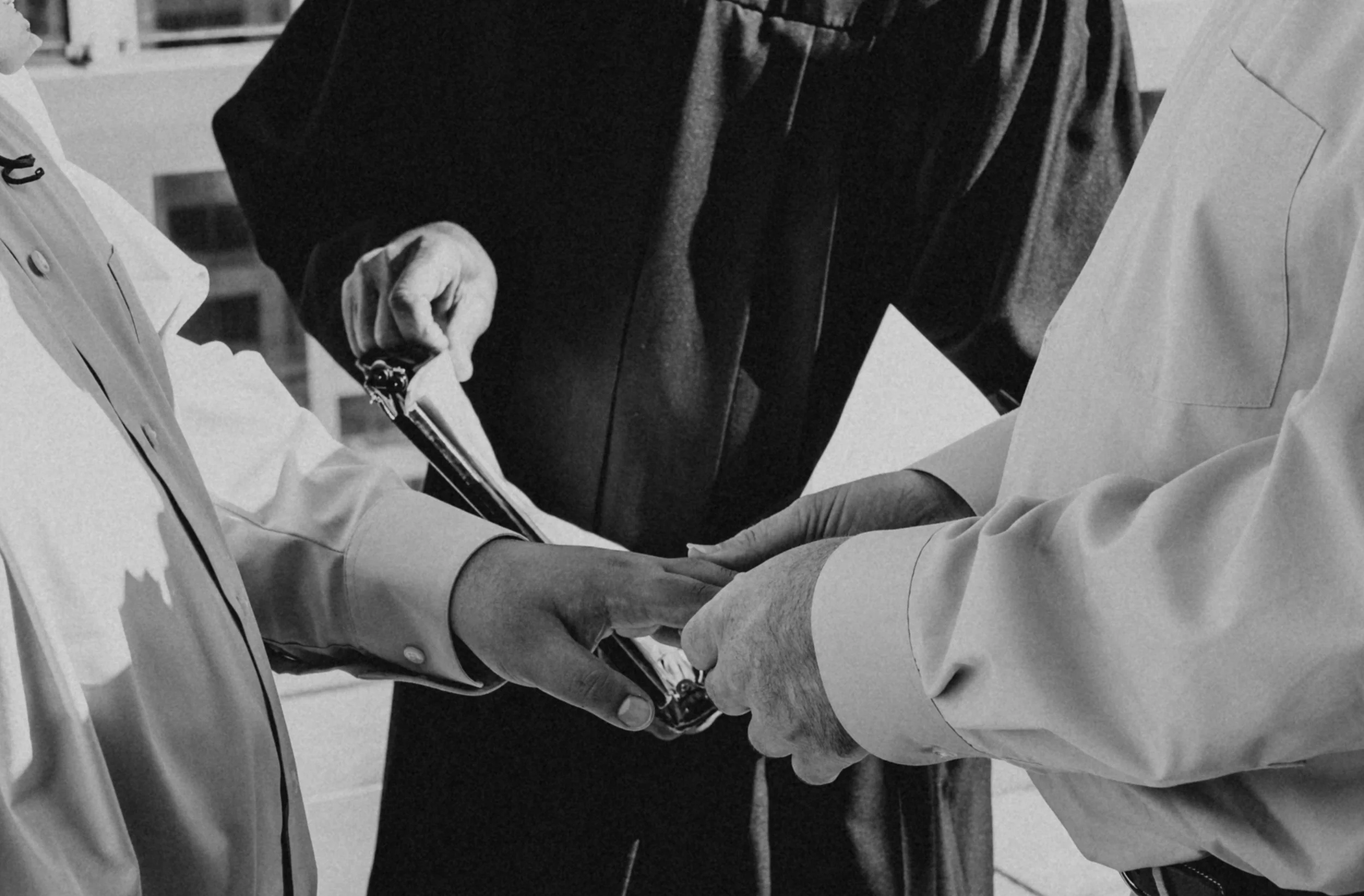Two people in medical uniforms exchanging a document, with a third person in dark clothing observing nearby. Seattle Municipal Courthouse wedding photography.