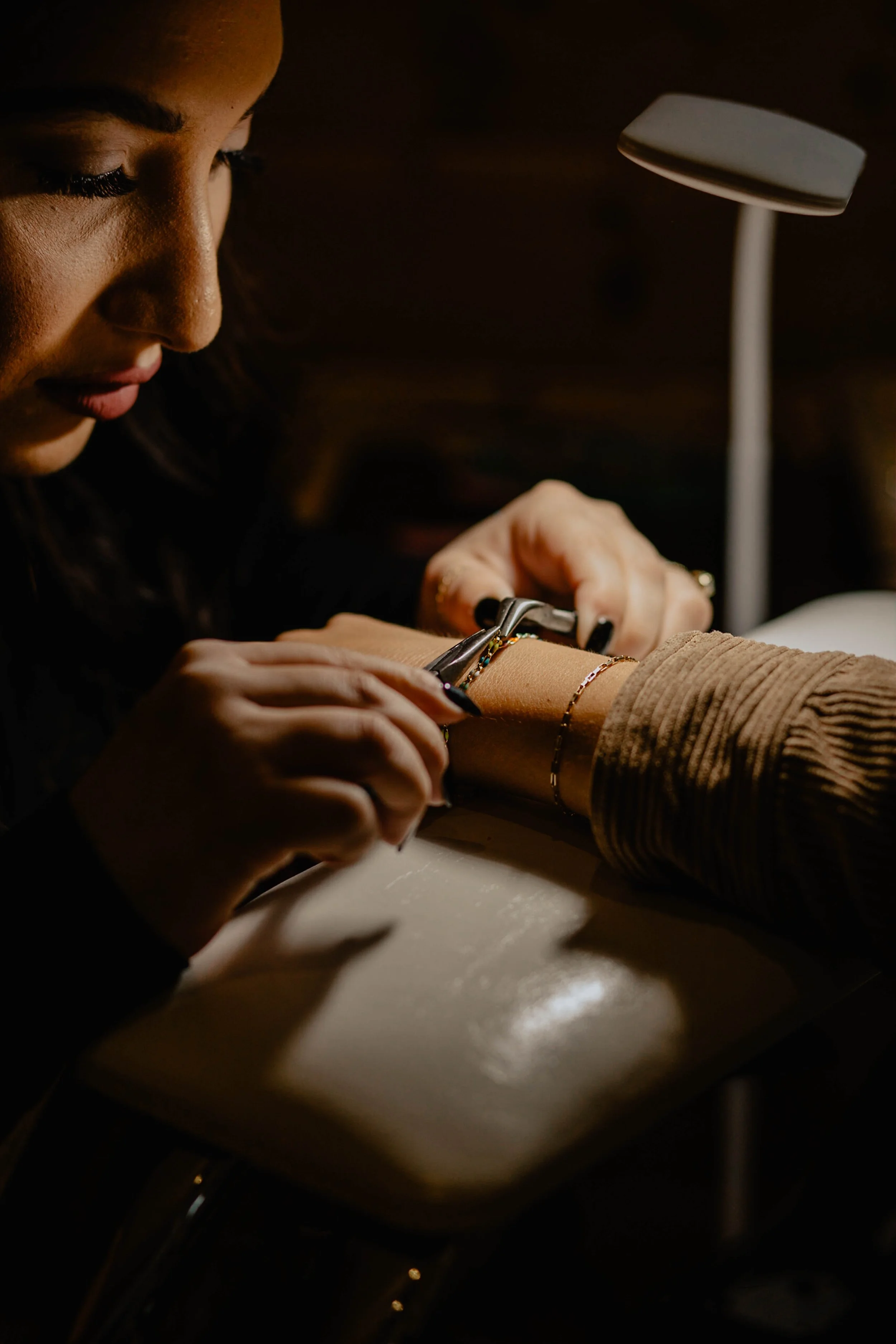 A woman is getting a manicure at a nail salon, with a focus on her hand and nails, under a small lamp for lighting. Seattle professional head shot photography