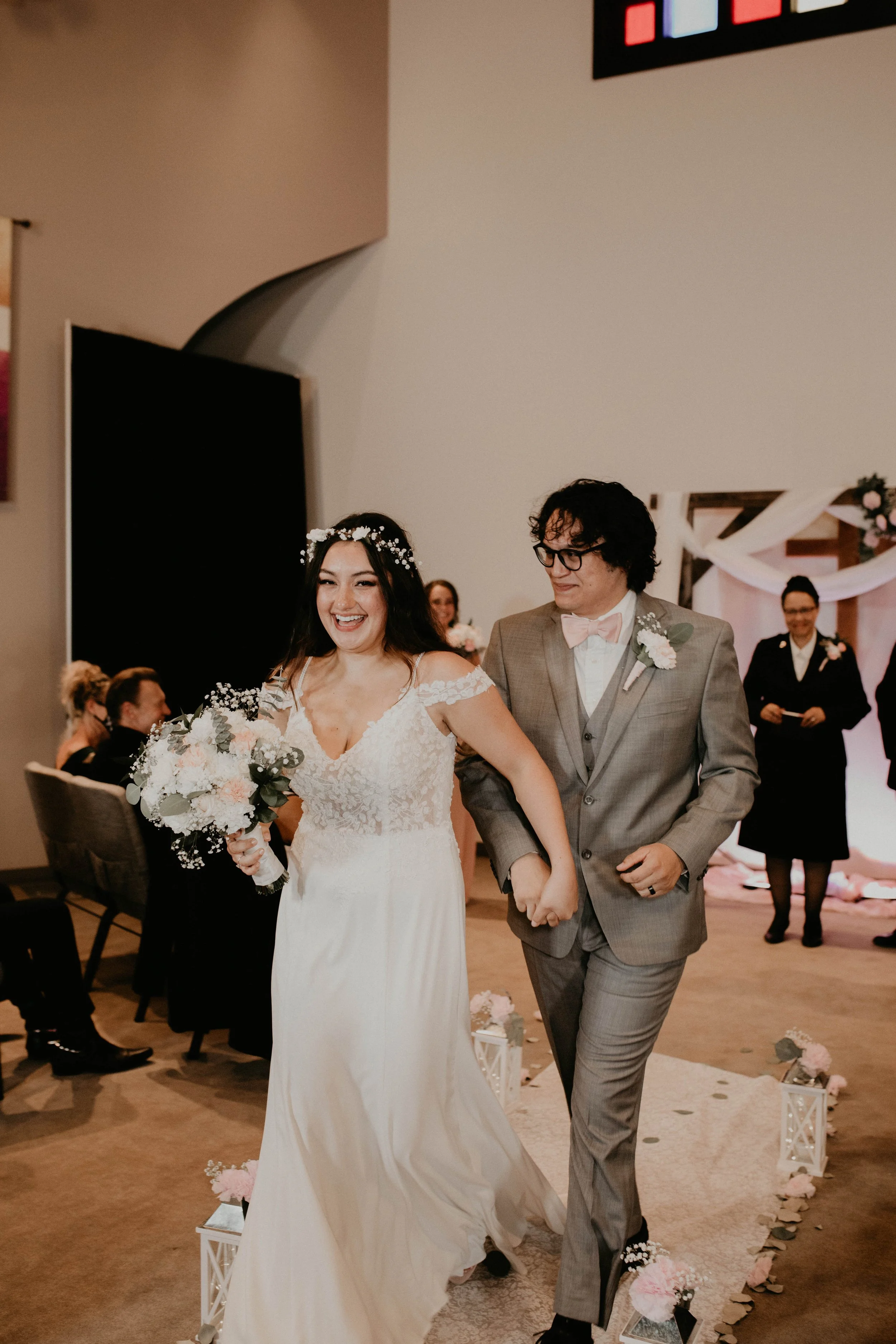 Bride and groom walking down the aisle at their wedding, holding hands and smiling, surrounded by guests and wedding decorations. Seattle, WA wedding photography.