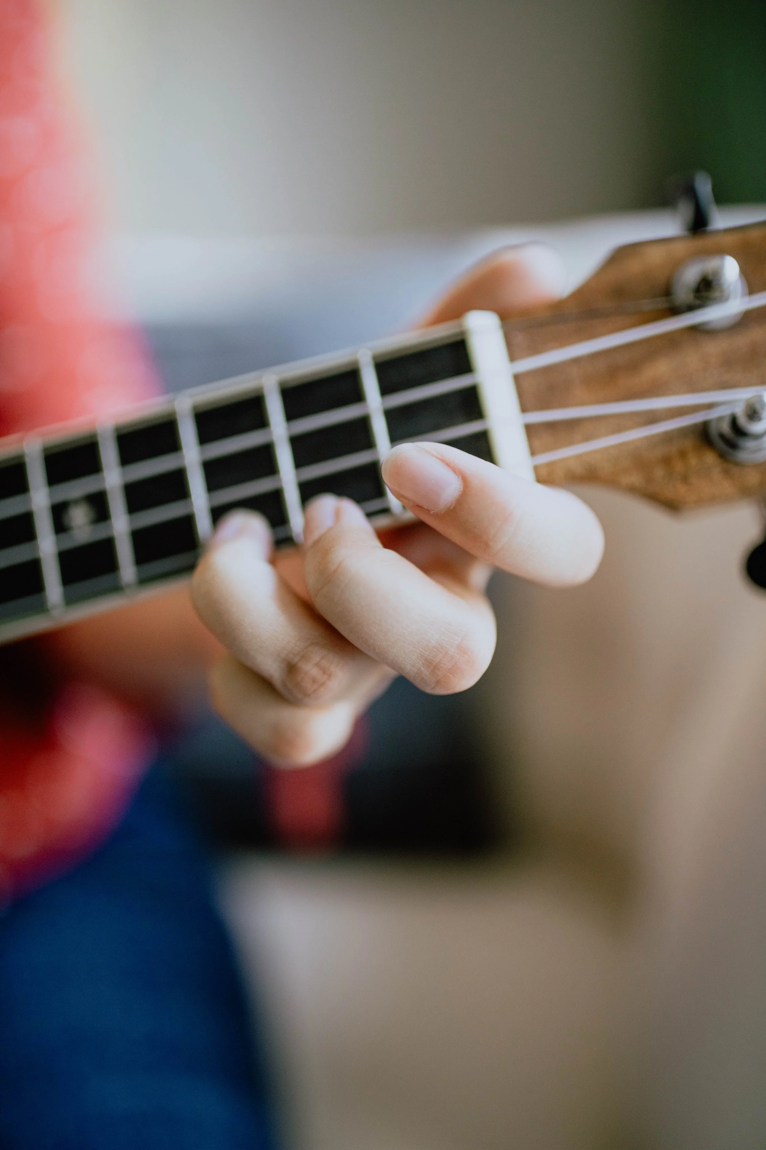 Close-up of a person's hand playing a guitar, focusing on the fingers on the fretboard. Seattle professional head shot photography