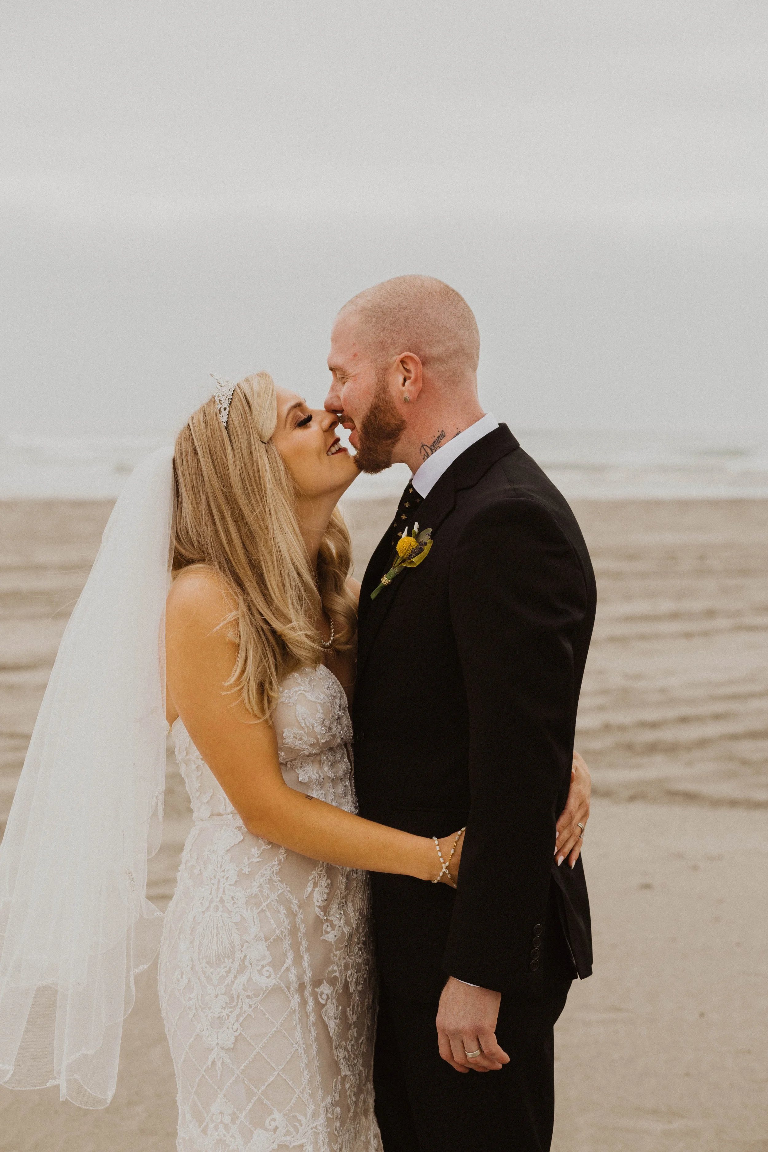 A bride and groom on the beach, about to kiss, with the ocean in the background. Long Beach, WA wedding photography.