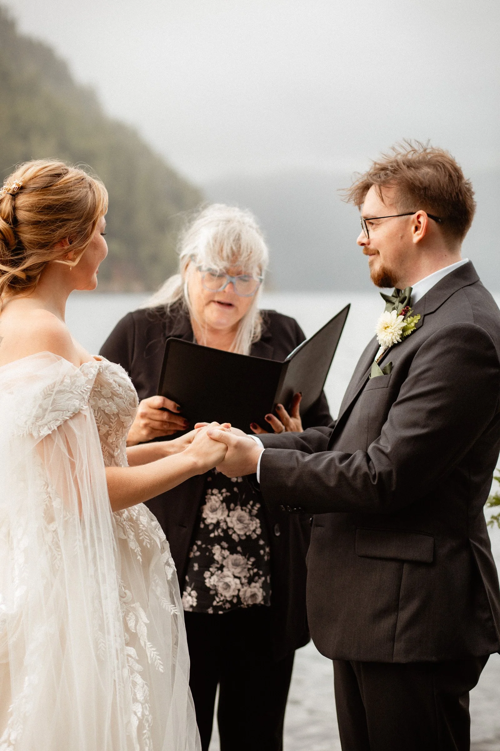 Groom holding the bride’s hands at the altar and smiling at her during their Lake Crescent Lodge wedding ceremony in Port Angeles, WA.