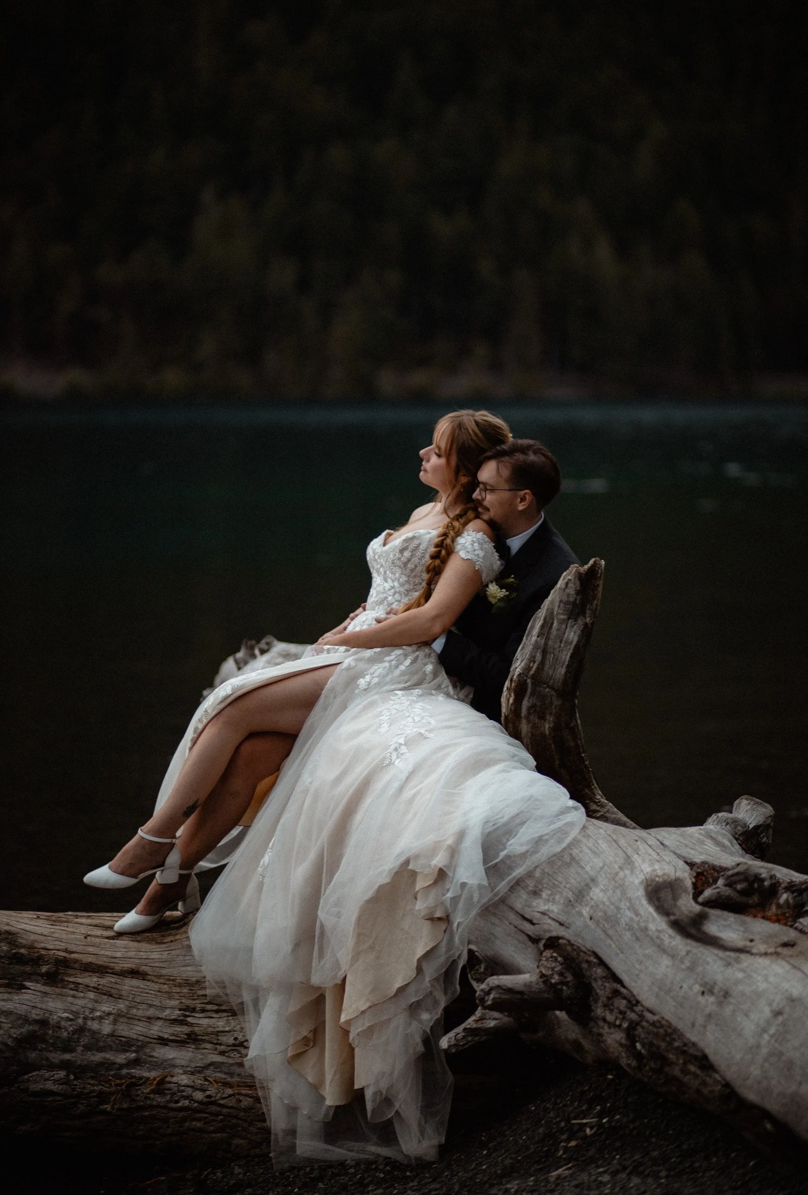 Bride and groom standing on a dock at Lake Crescent with mountains reflected in the water during their Lake Crescent Lodge wedding in Port Angeles, WA.