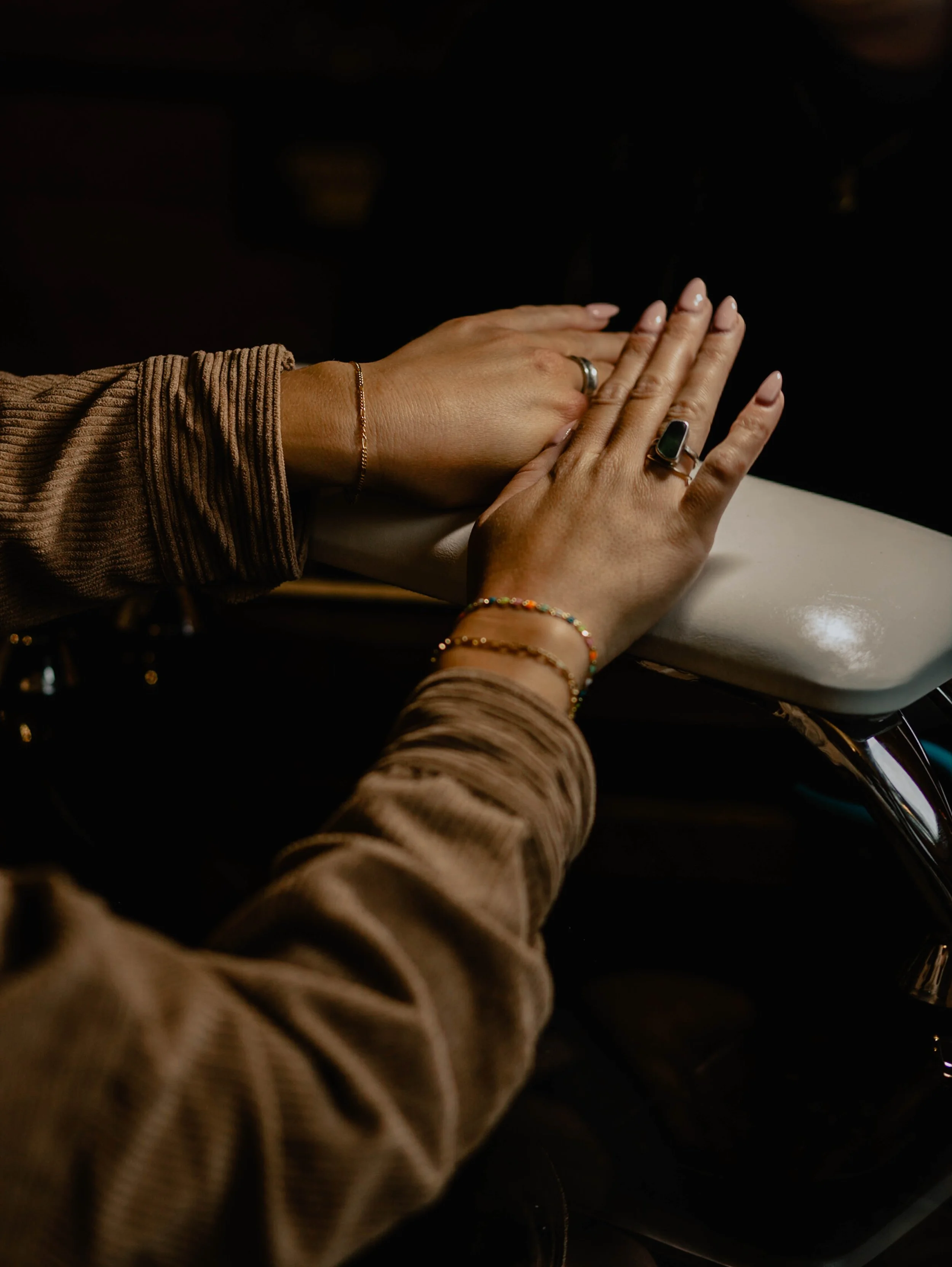 Two hands with rings and bracelets gently placed on a white surface, against a dark background. Seattle professional head shot photography