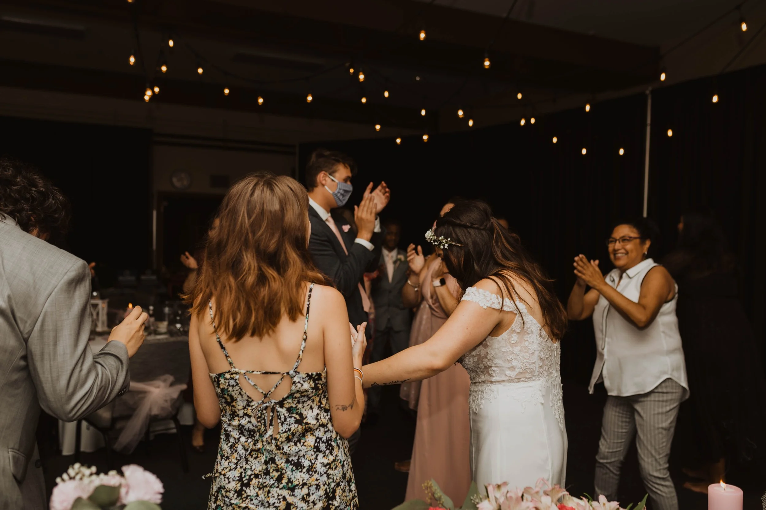 People celebrating at a wedding reception, dancing and smiling in a decorated indoor venue. Seattle, WA wedding photography.