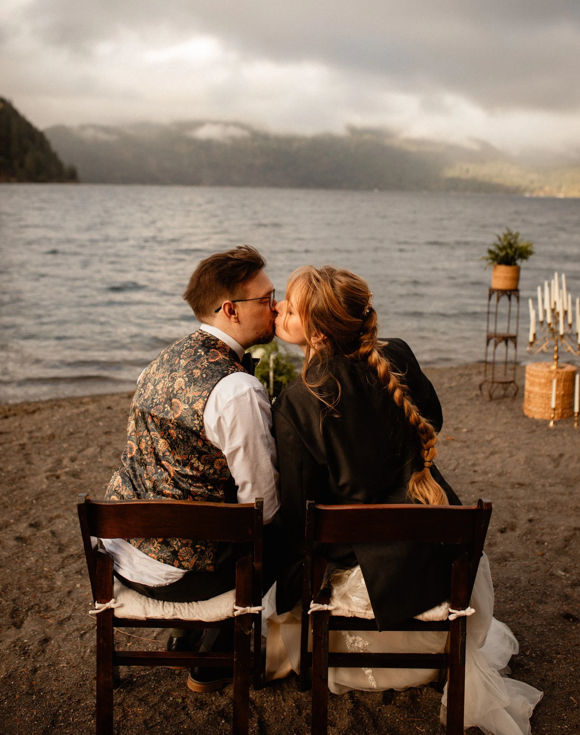 Bride and groom sharing a kiss while sitting in chairs during their intimate lakeside reception at Lake Crescent Lodge in Port Angeles, WA.