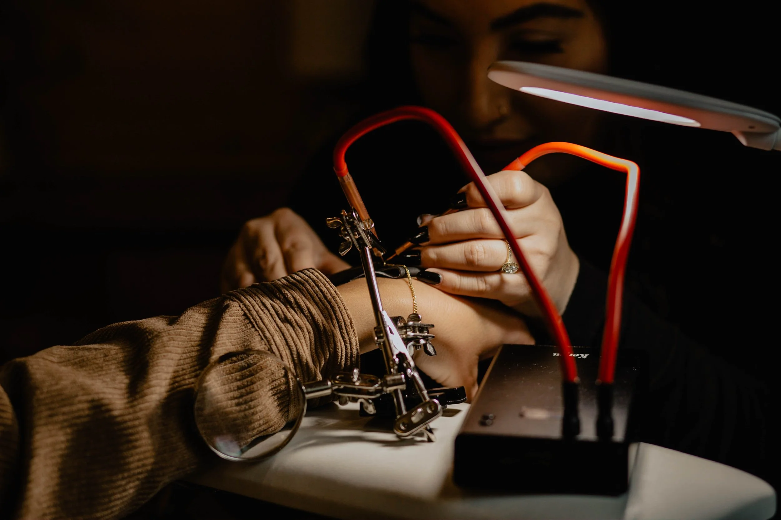 Person receiving a tattoo on their forearm during a tattooing process, with a tattoo artist using a tattoo machine under a bright light. Seattle professional head shot photography