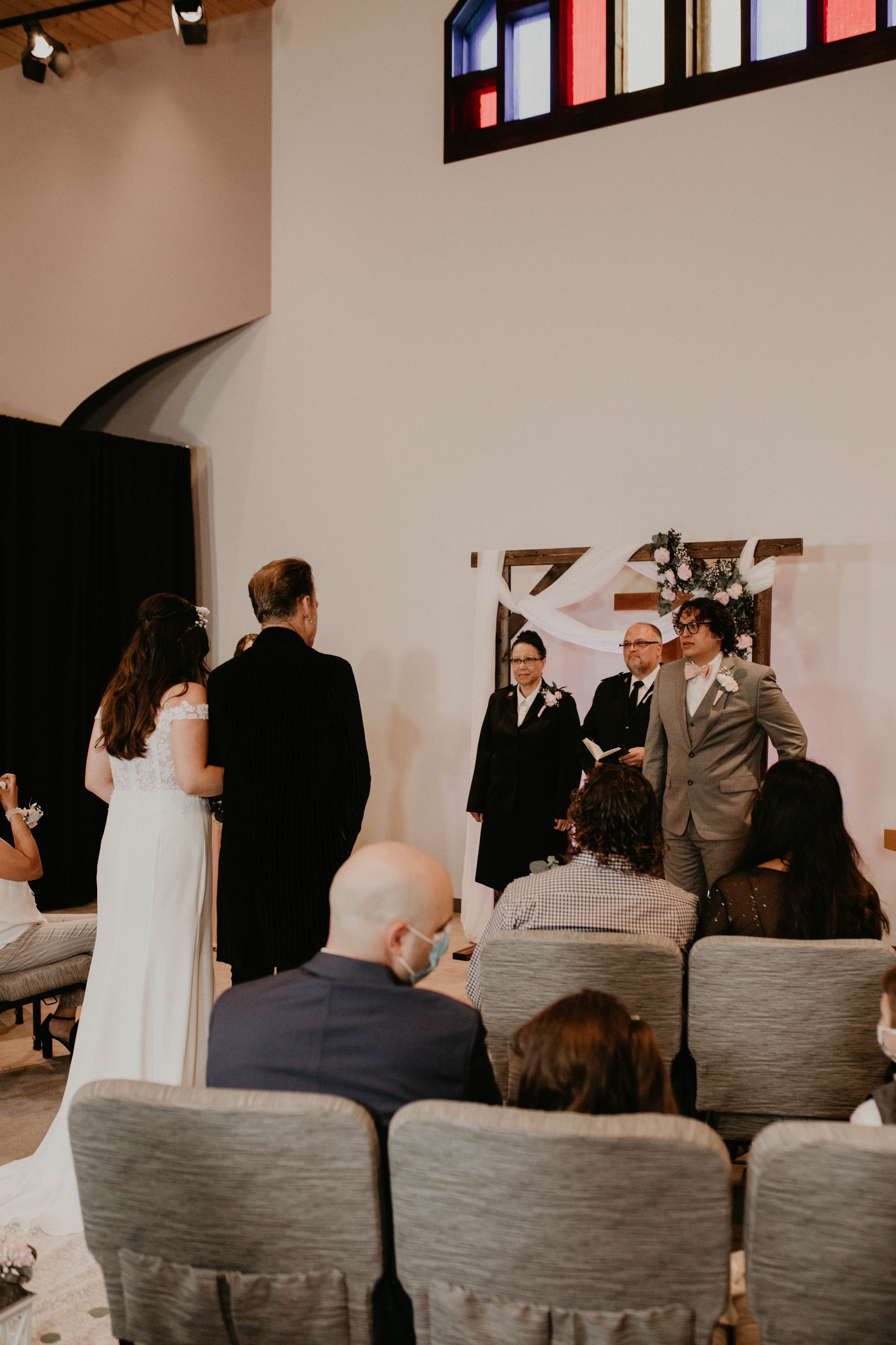 A crowd at a wedding ceremony with a bride, groom, and officiant in front of a decorated backdrop. Seattle, WA wedding photography.