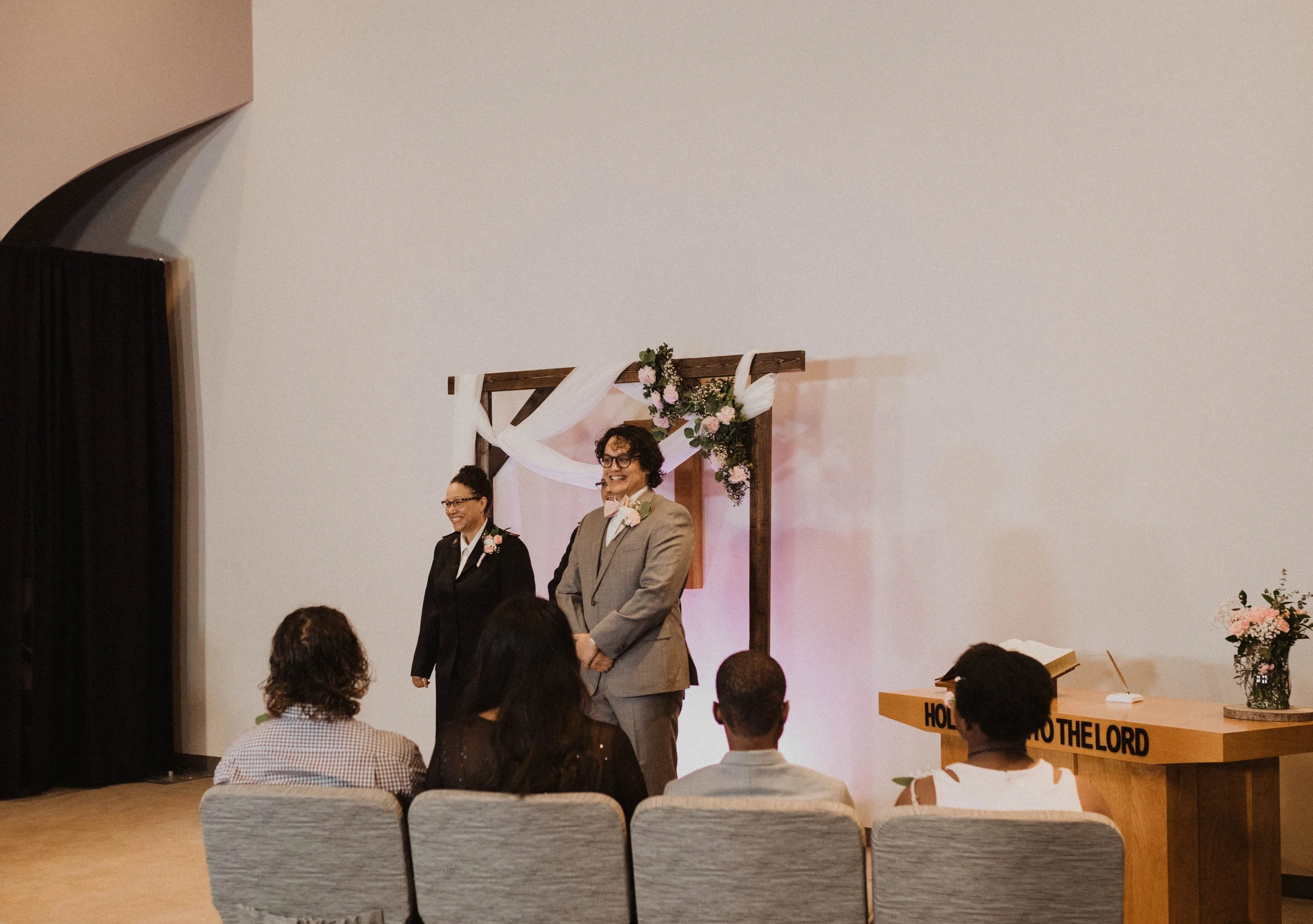 A wedding ceremony with officiant and officiant standing in front of guests in a decorated venue. Seattle, WA wedding photography.
