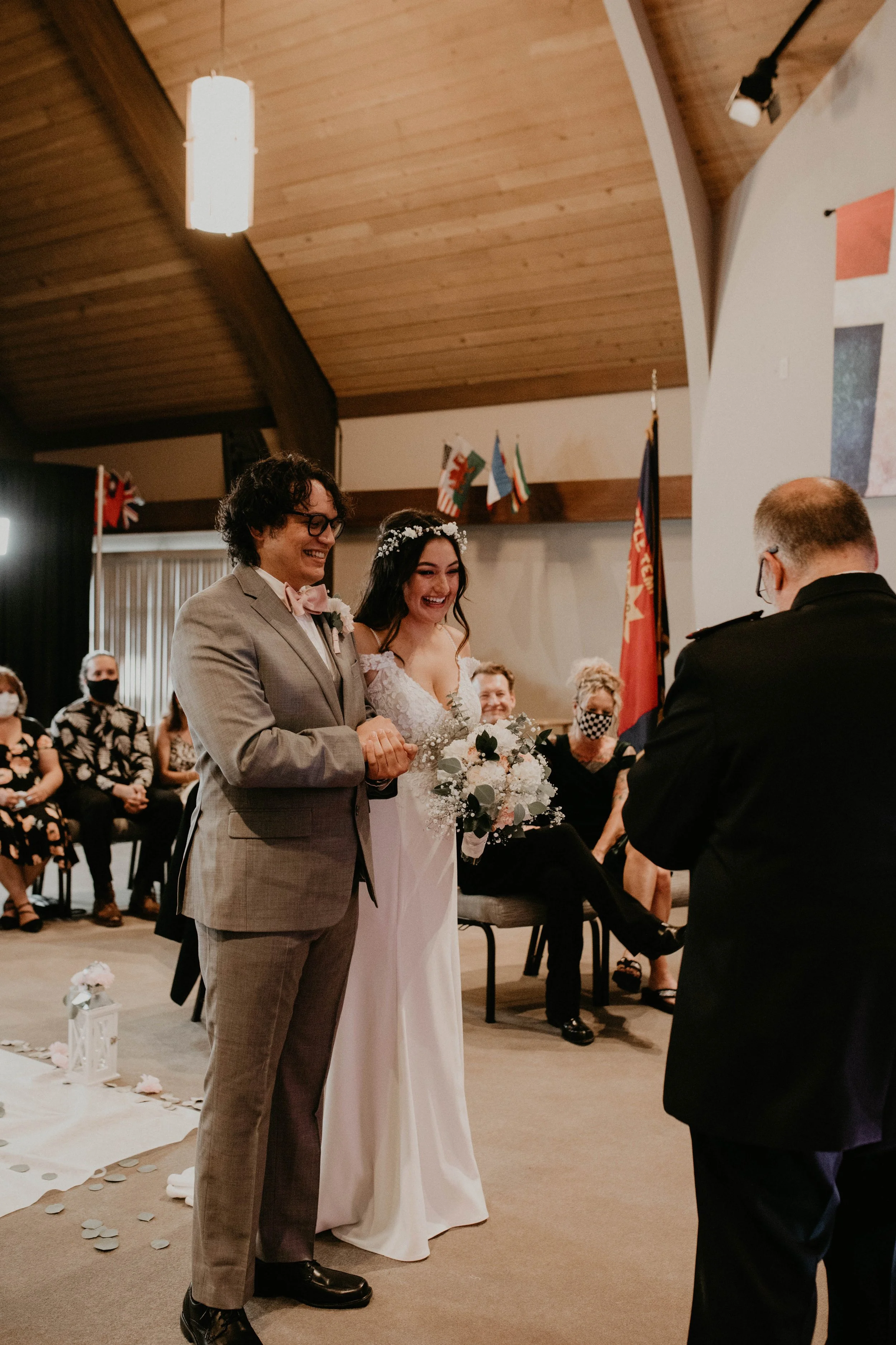 Bride and groom exchanging vows at a wedding ceremony indoors, with seated guests in the background. Seattle, WA wedding photography.