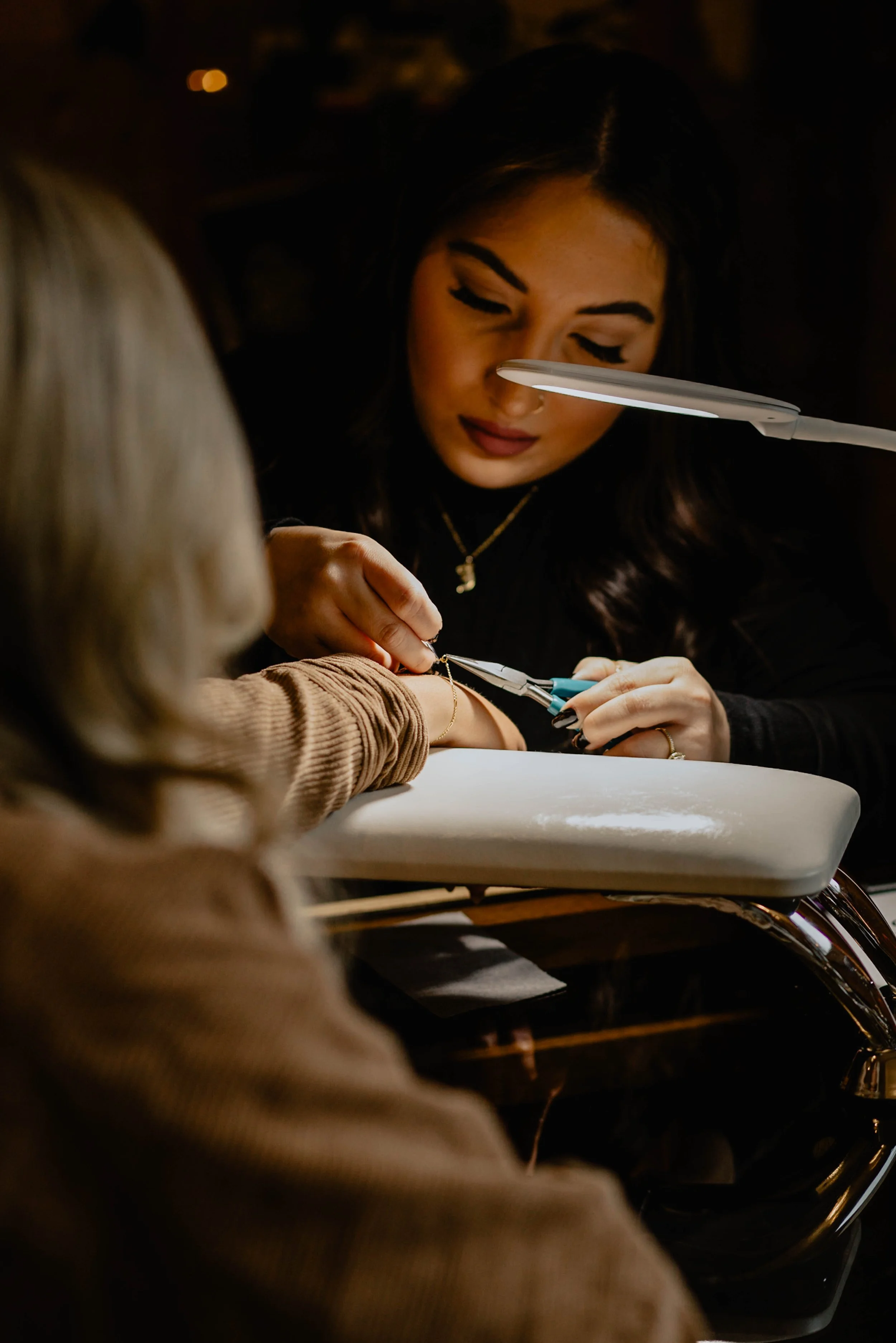 A woman getting a manicure at a nail salon, with a nail technician working on her nails under a bright light. Seattle professional head shot photography