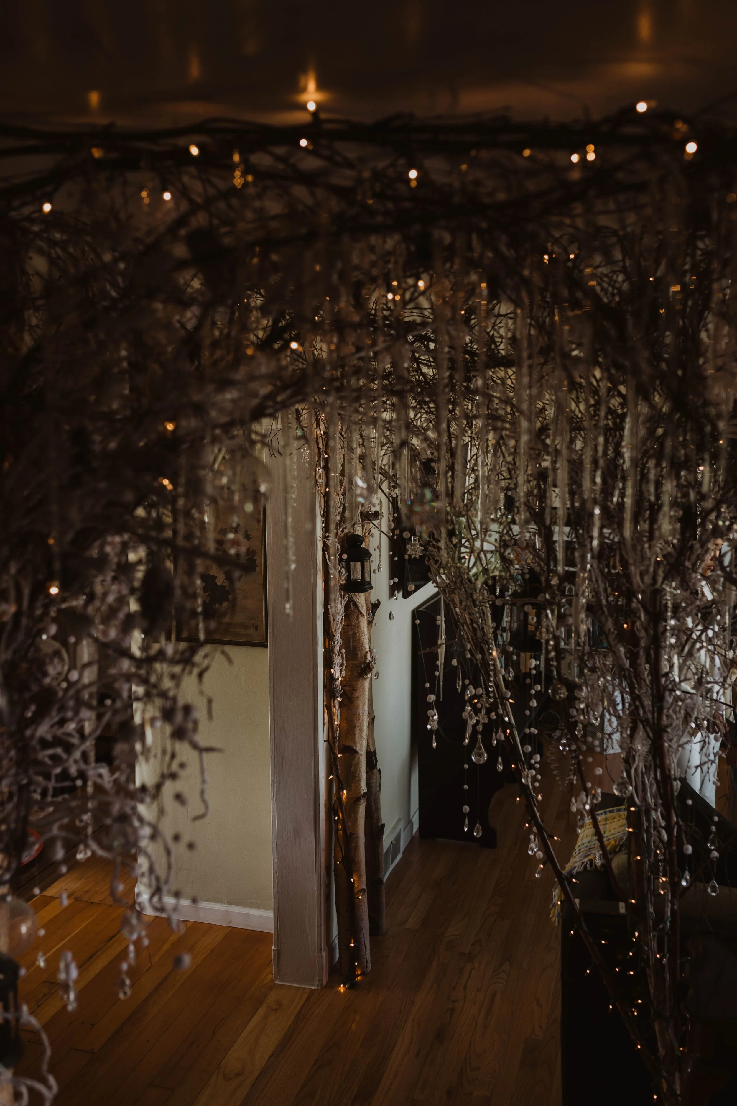 Decorated indoor space with hanging branches, fairy lights, and crystal ornaments, creating a festive or wintery atmosphere. Seattle, WA wedding photography.