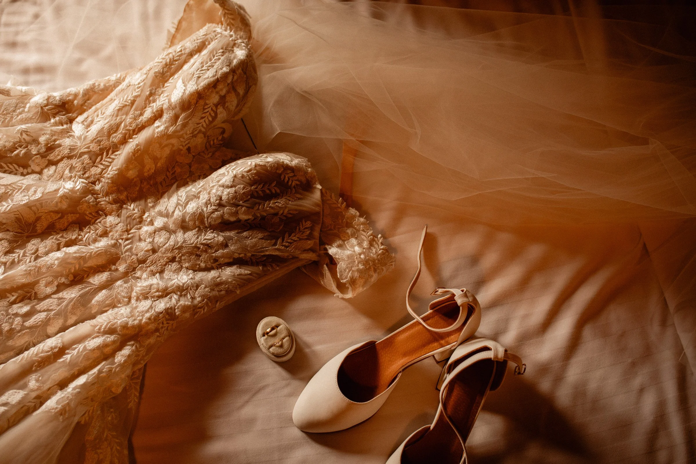 Wedding dress and bridal shoes on the bed in the Lake Crescent Lodge bridal suite before a Lake Crescent wedding in Port Angeles, WA.