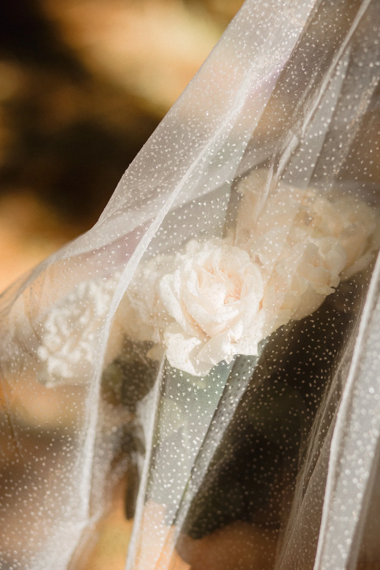 A close up image of a shimmery veil covering the bride. You can see her veil drapped over her hands which hold her simple, white bouquet. In moments she will walk down the aisle on her wedding day at Lake Crescent, in Port Angeles, WA.