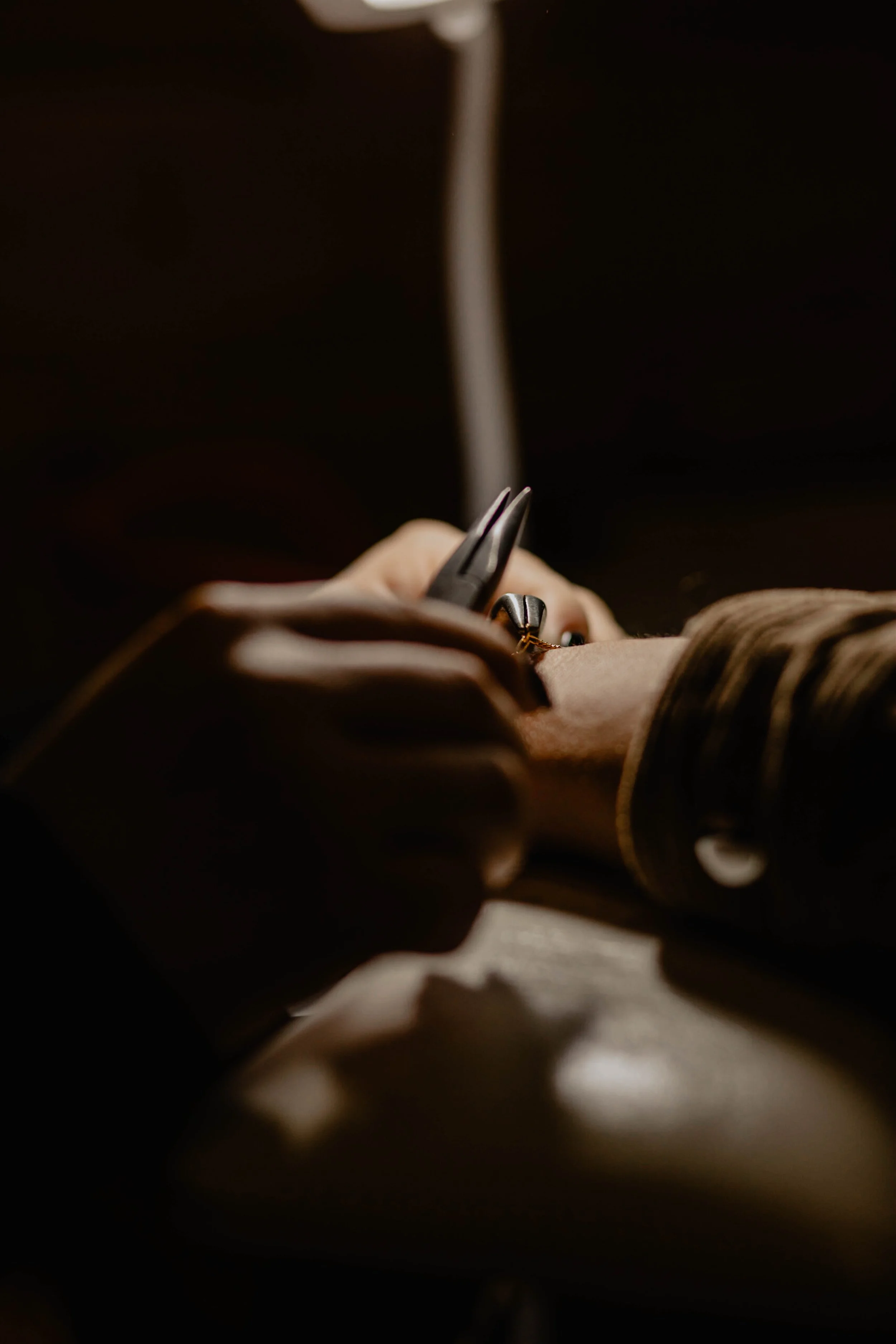 Close-up of a person using pliers to work on jewelry or small craft project in low light. Seattle professional head shot photography