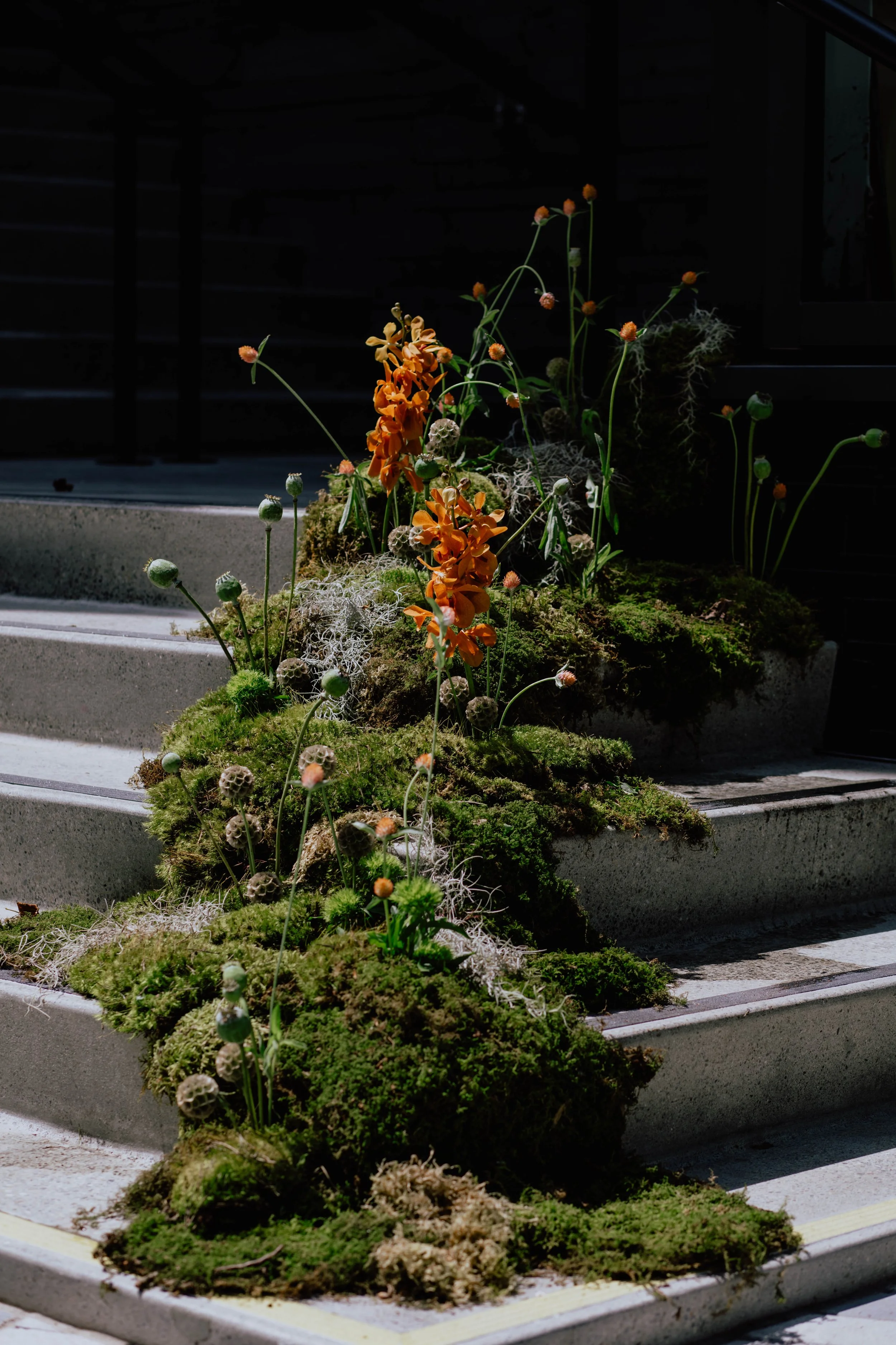 A staircase decorated with moss and orange flowers, with dark background. Seattle event photography