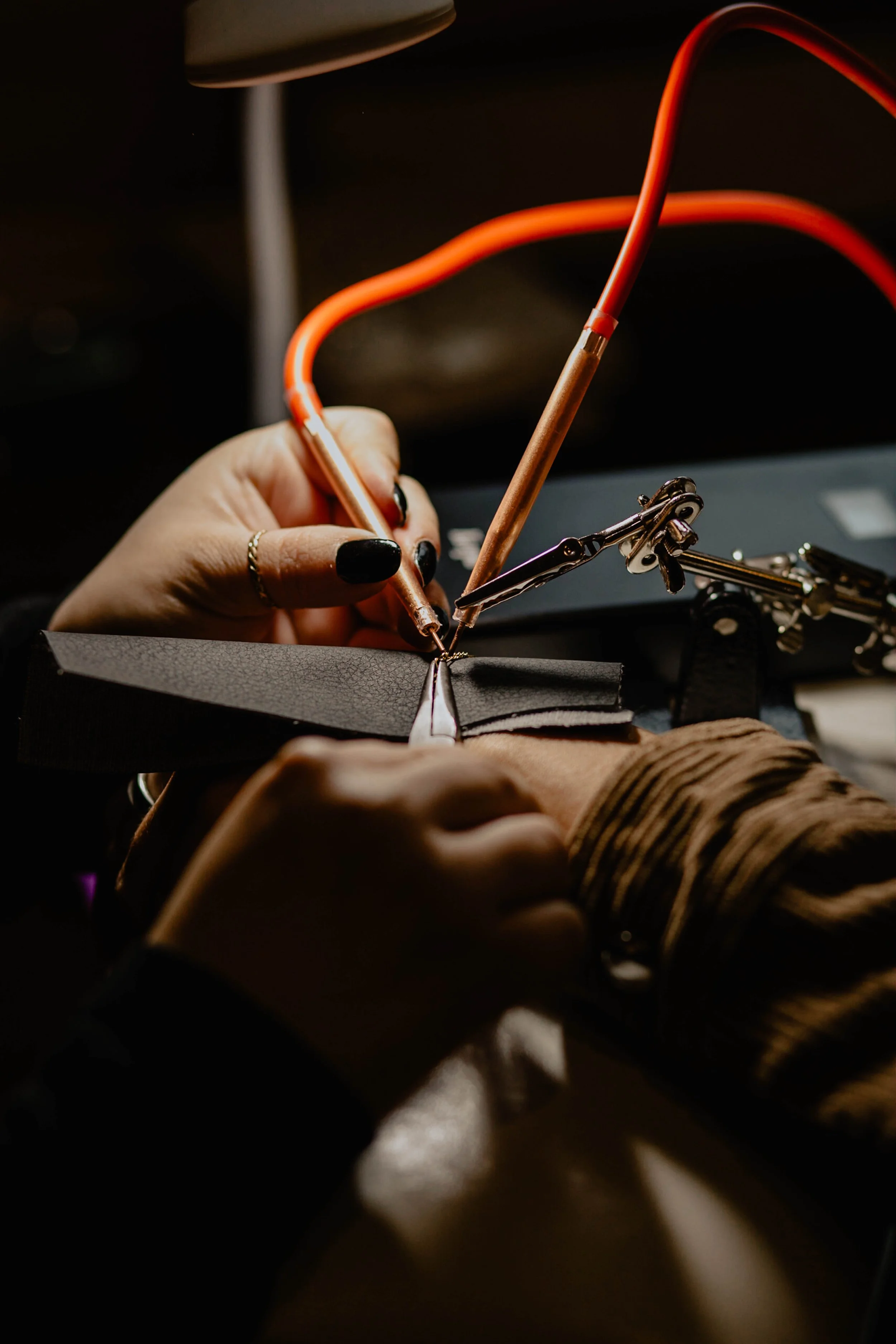 Close-up of a person soldering with a soldering iron and helping hands tool in a dark workspace. Seattle professional head shot photography