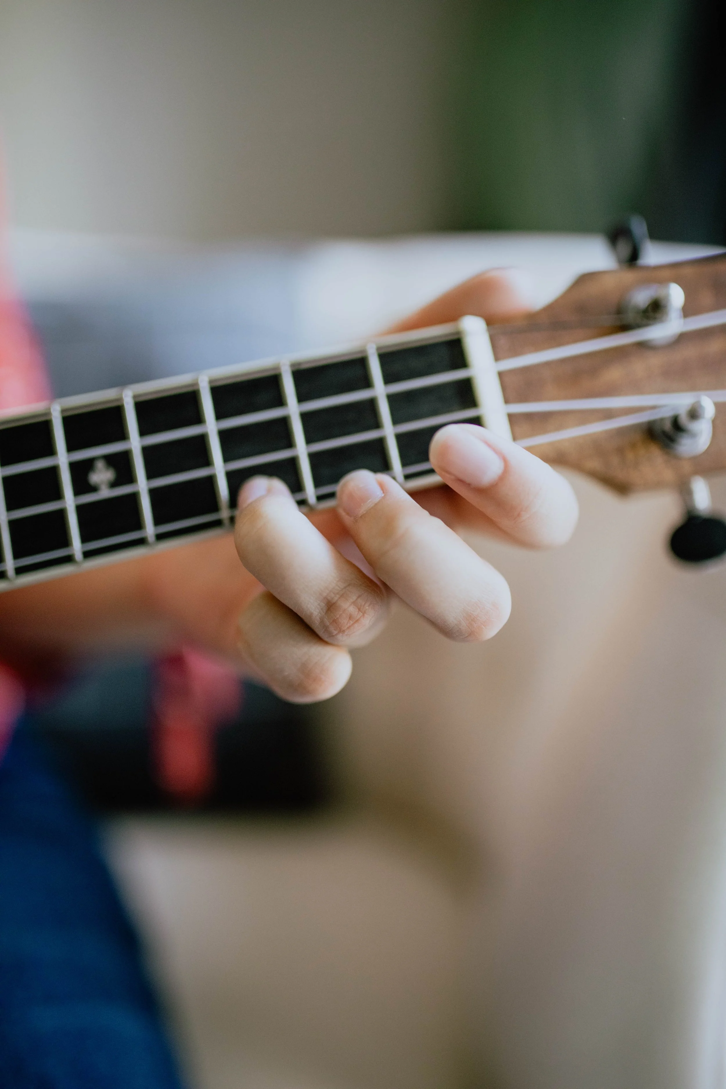 Close-up of a person playing an acoustic guitar, focusing on the fingers pressing down on the fretboard. Seattle professional head shot photography