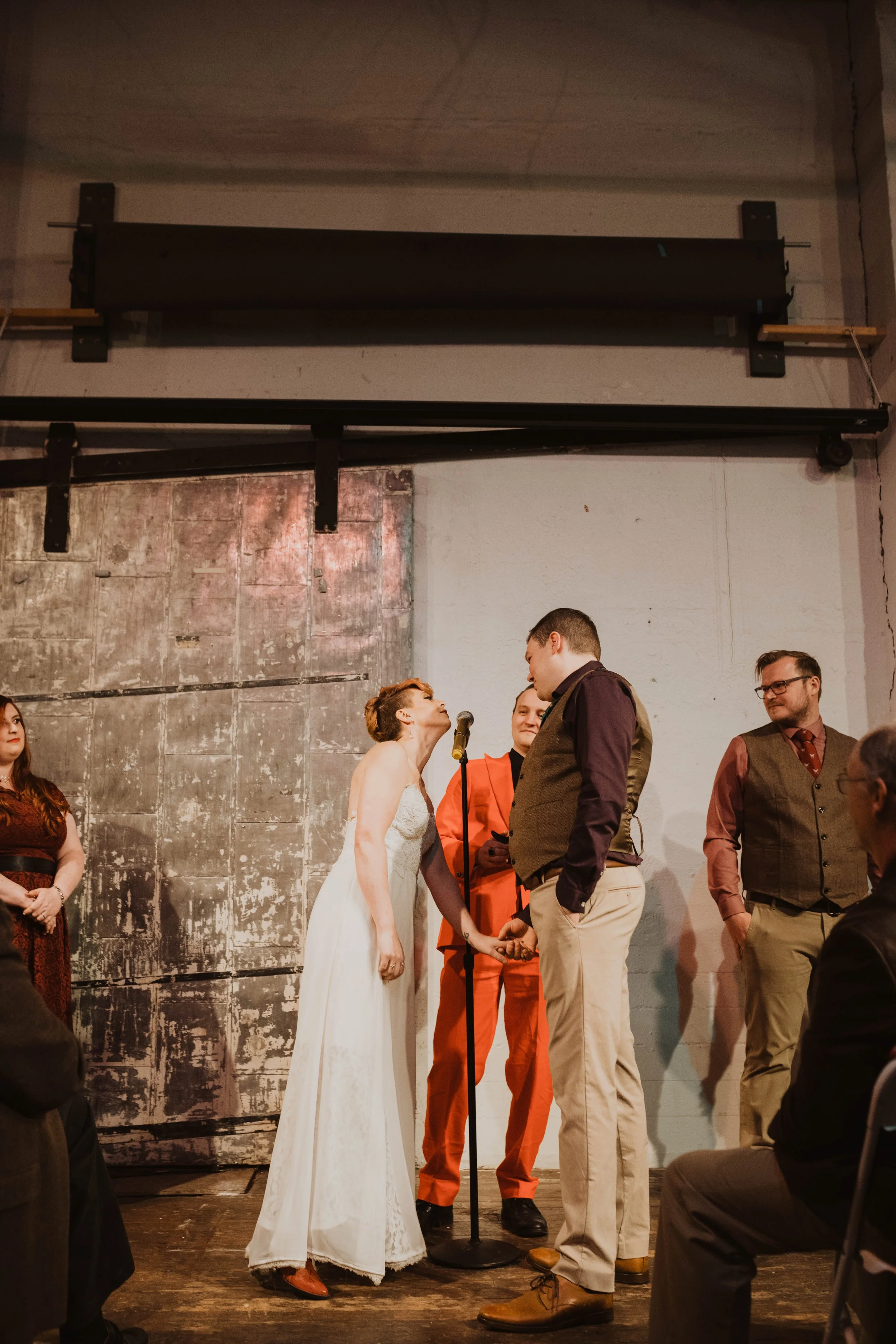 A couple gets married during a wedding ceremony on a stage, with the officiant and witnesses present, while guests watch. Pioneer Square, Seattle, WA wedding photography.