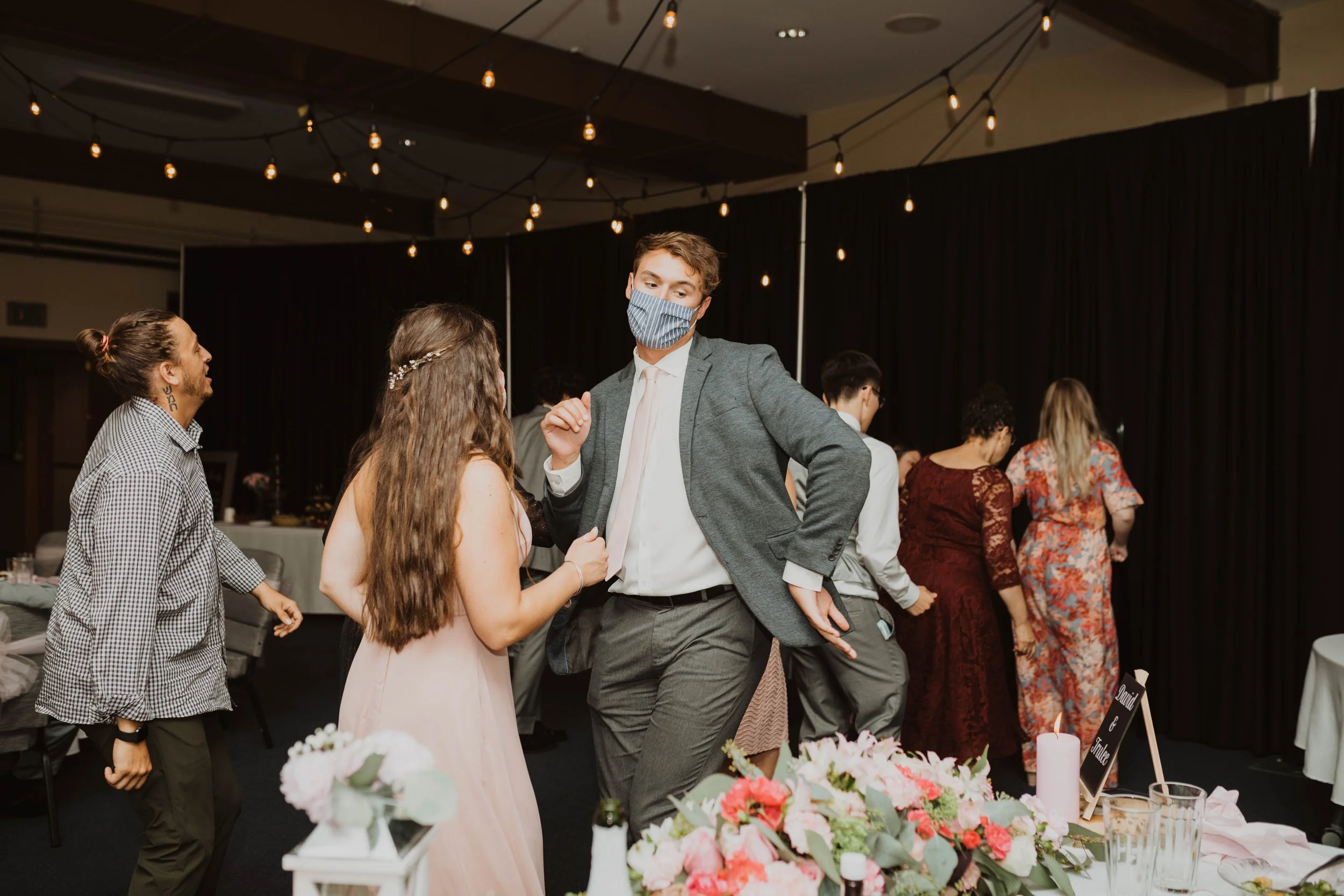 People dancing at a wedding reception with decorative flowers and string lights. Seattle, WA wedding photography.