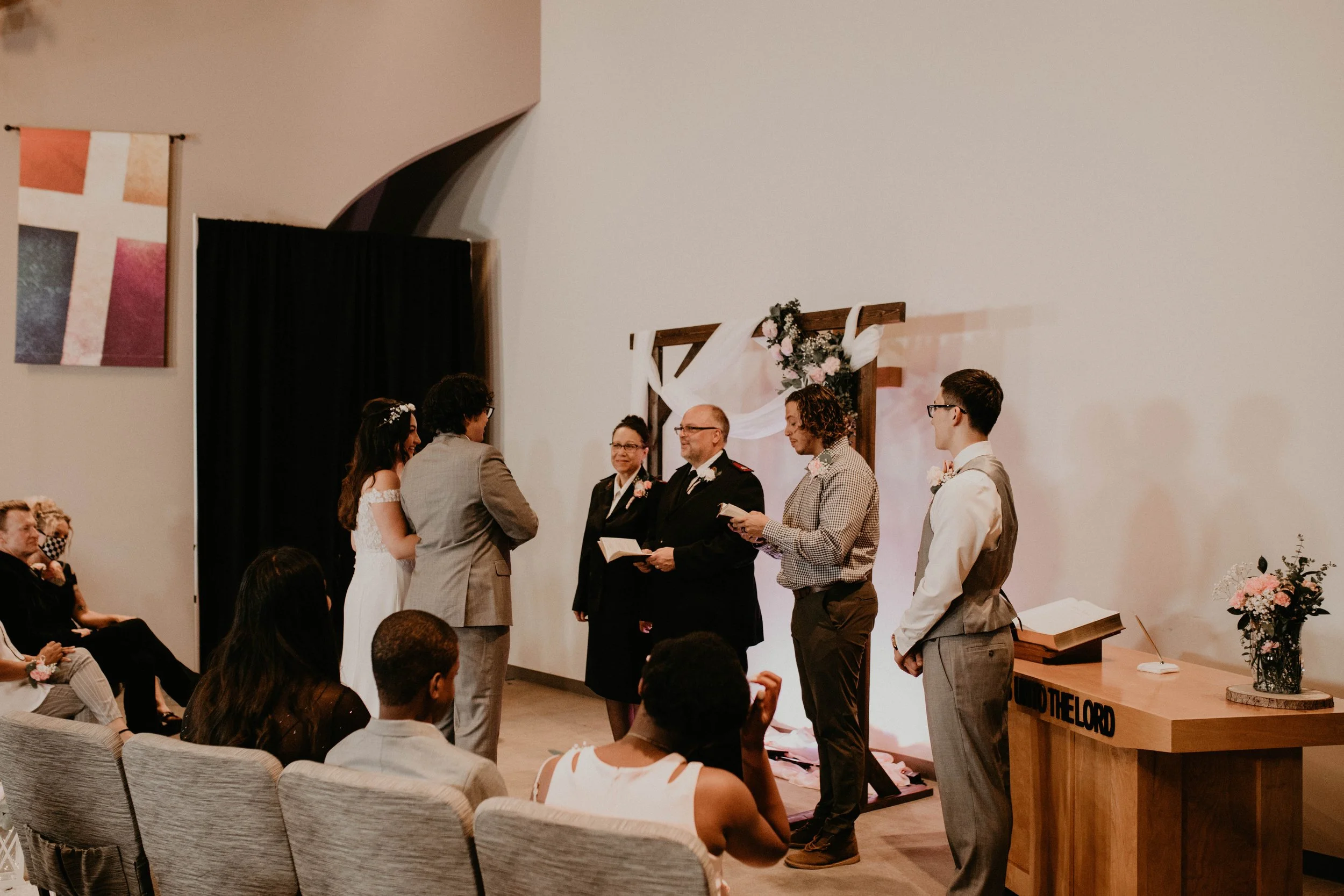 A couple getting married at a wedding ceremony in front of officiants and witnesses, with guests seated watching. Seattle, WA wedding photography.