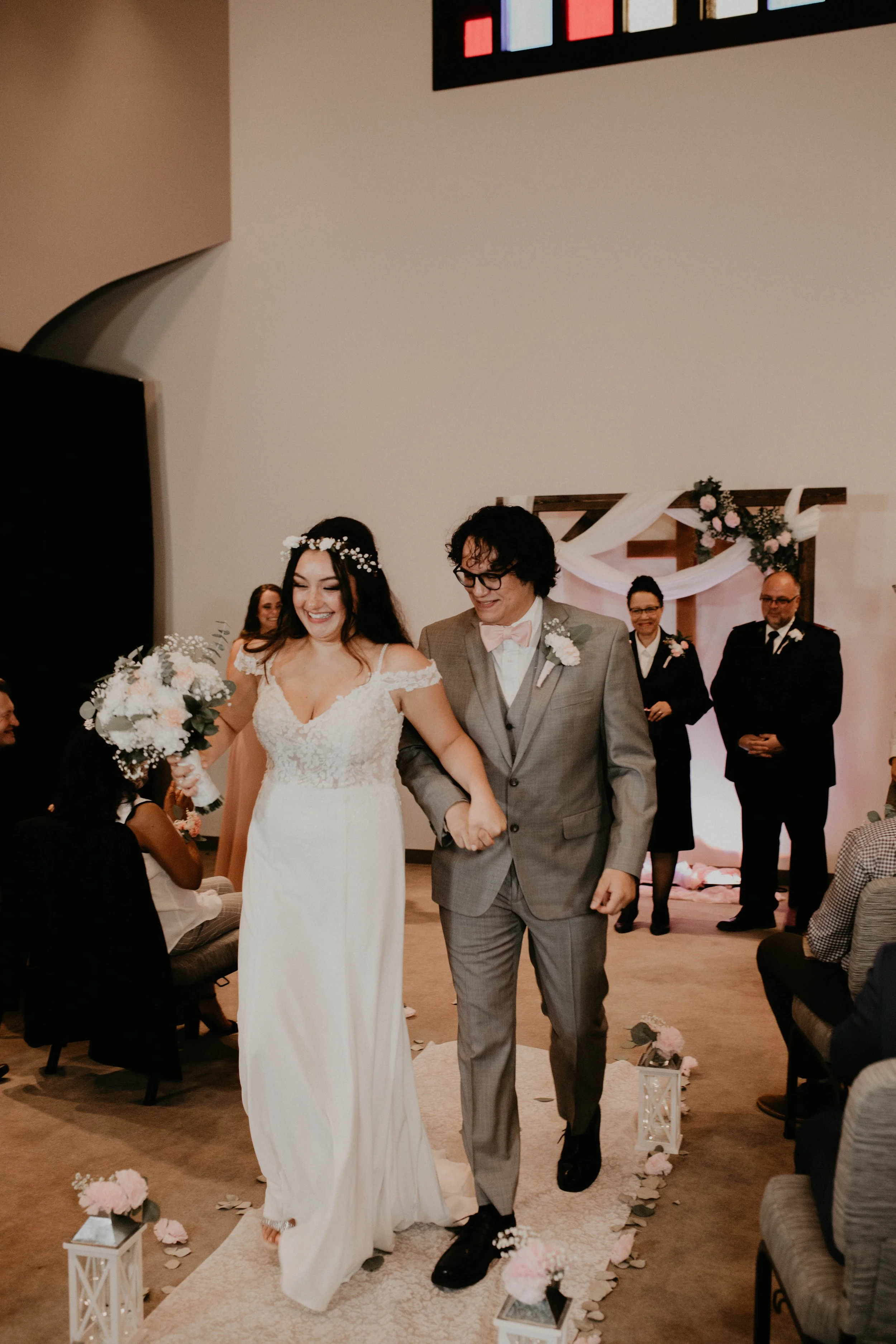 A bride and groom walking down the aisle during wedding ceremony, smiling, with wedding party and guests in the background. Seattle, WA wedding photography.