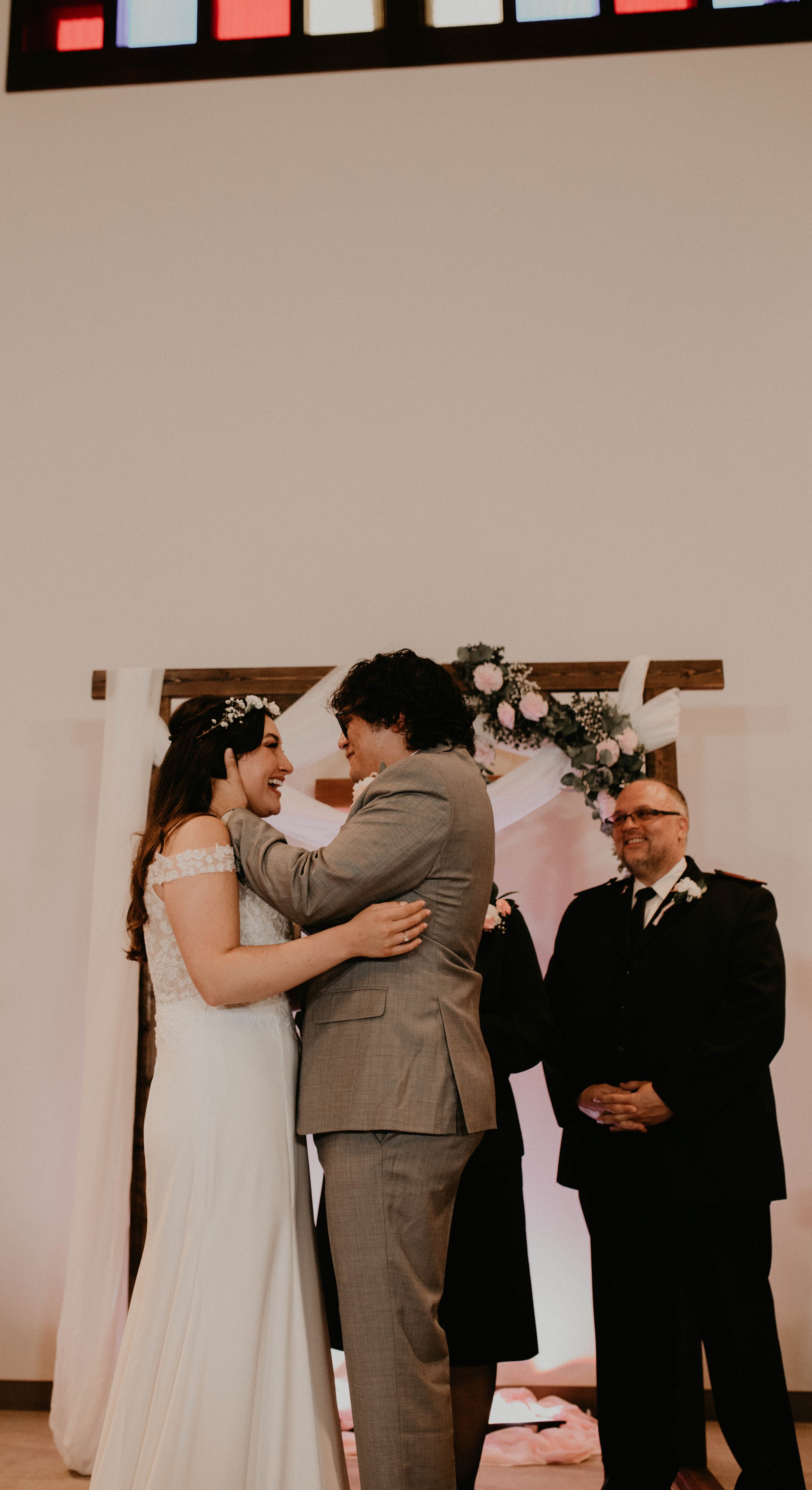 Bride and groom exchanging vows at wedding ceremony, with officiant standing behind them, decorated with flowers and fabric arch. Seattle, WA wedding photography.