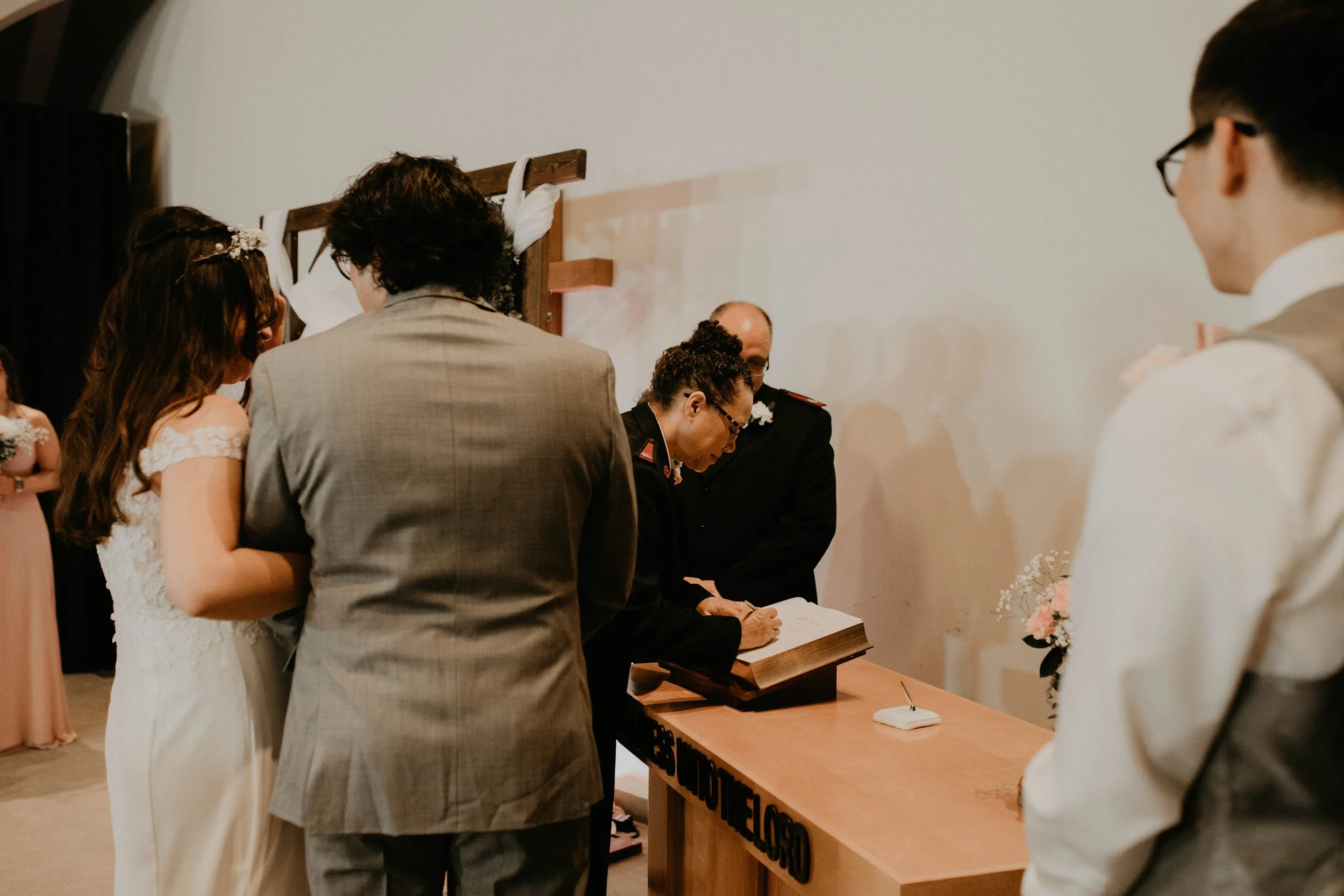 Couple getting married, standing before a religious officiant at a wedding ceremony, with wedding party members and guests present. Seattle, WA wedding photography.
