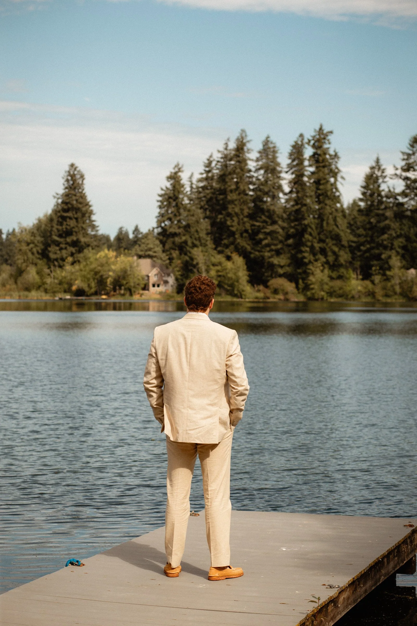 Groom awaits for his first look of his bride. He's standing on the lake dock at their wedding venue in Seattle, WA