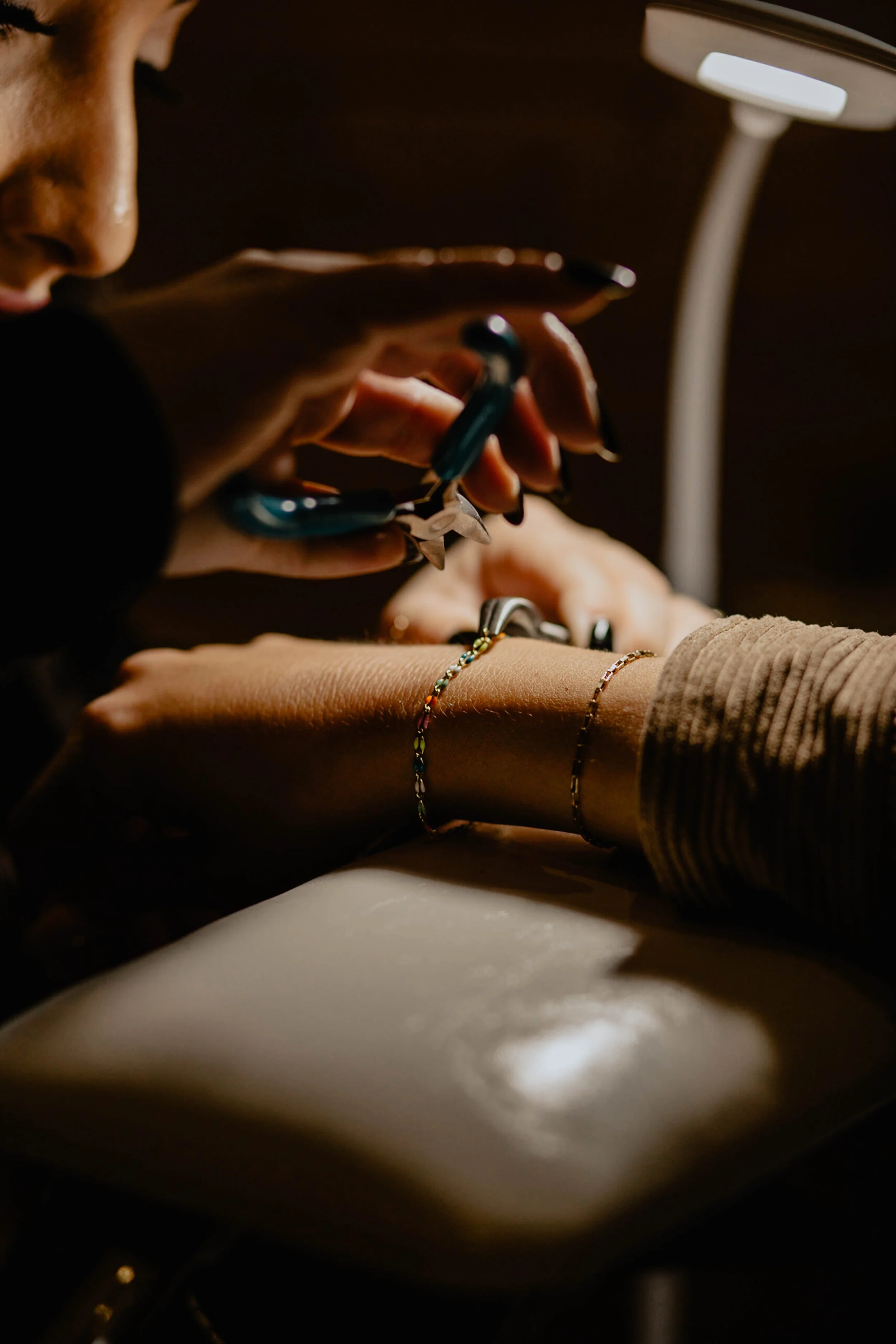 A manicurist painting a client's nails under a bright lamp. Seattle professional head shot photography